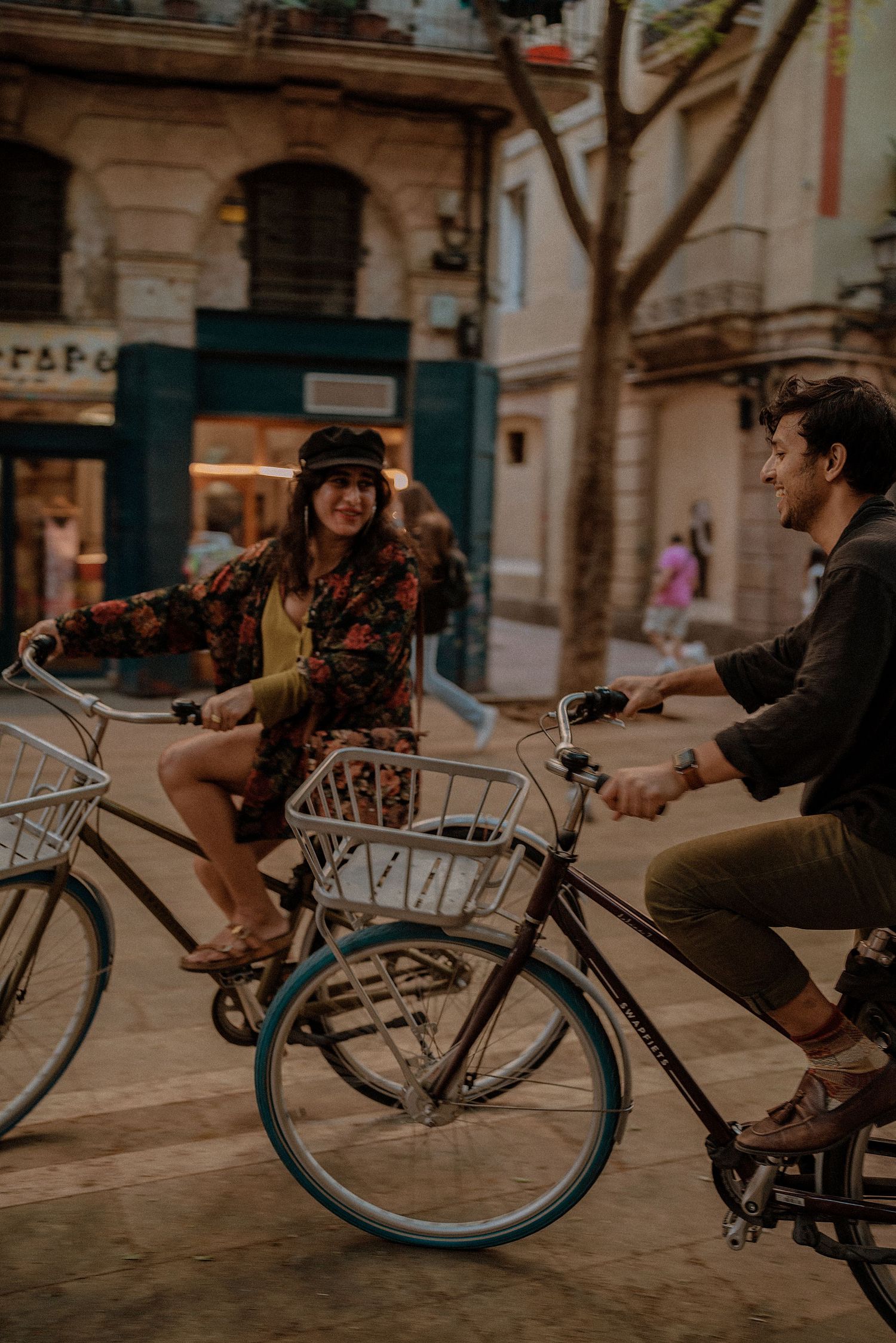 Playful couple riding bicycles together on a European city street.