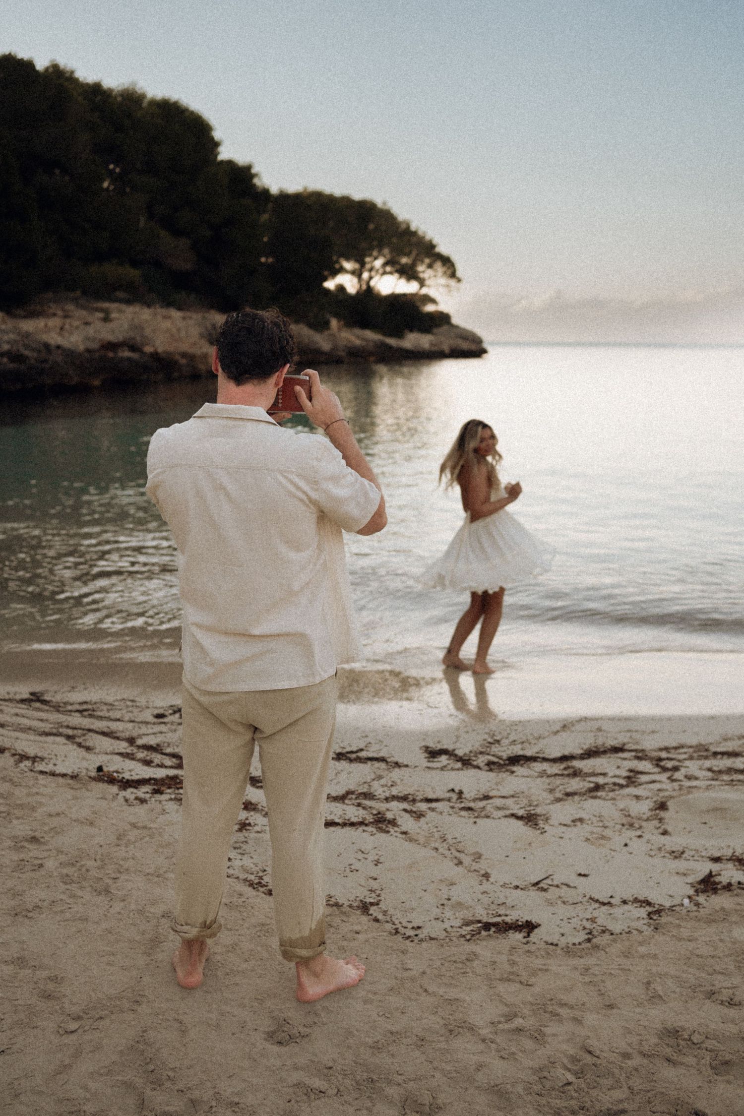 Two people share a carefree moment dancing on the beach during golden hour.