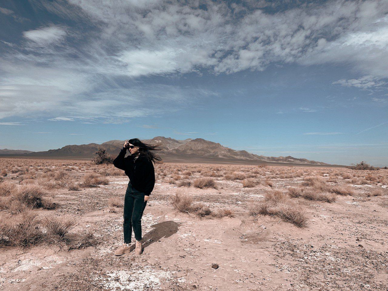 Sweeping desert landscape panorama showing seven perspectives of a person exploring rugged arid terrain under cloudy skies.