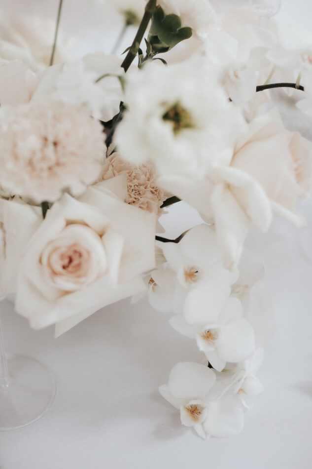 Close-up of delicate white and blush roses and orchids in an elegant wedding bouquet arrangement.