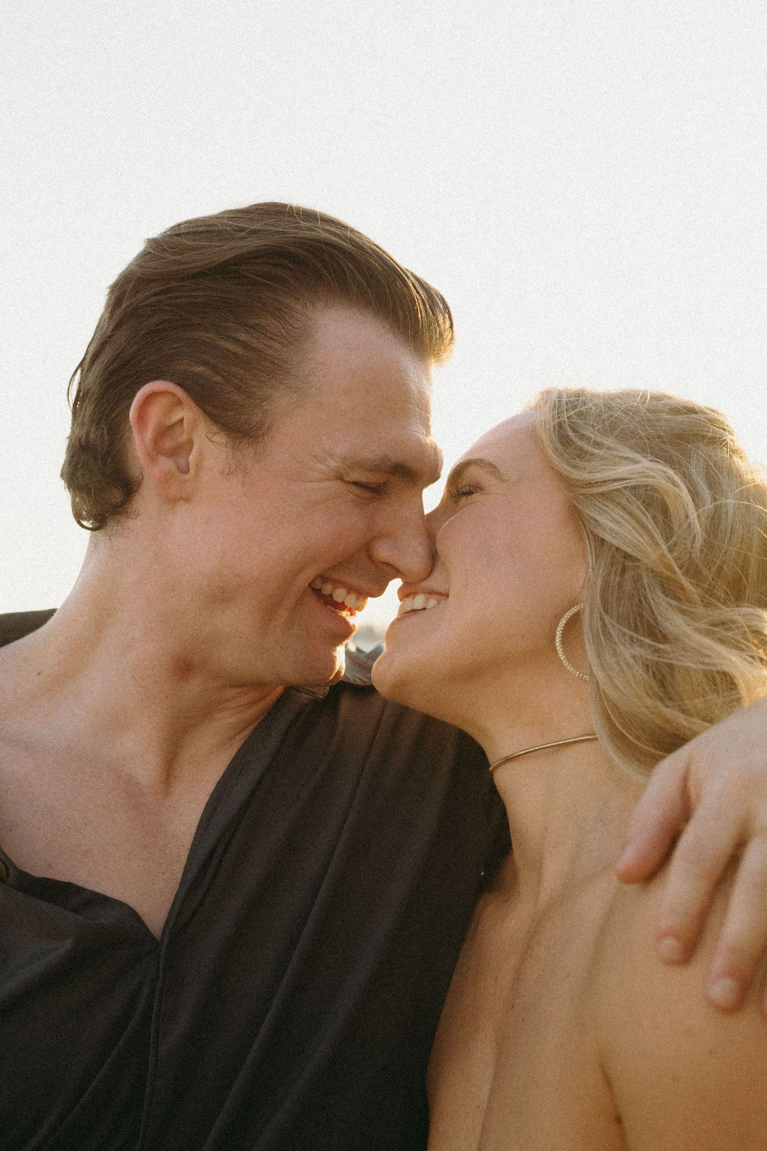 Loving couple captured in profile sharing romantic moments against sunset backdrop.