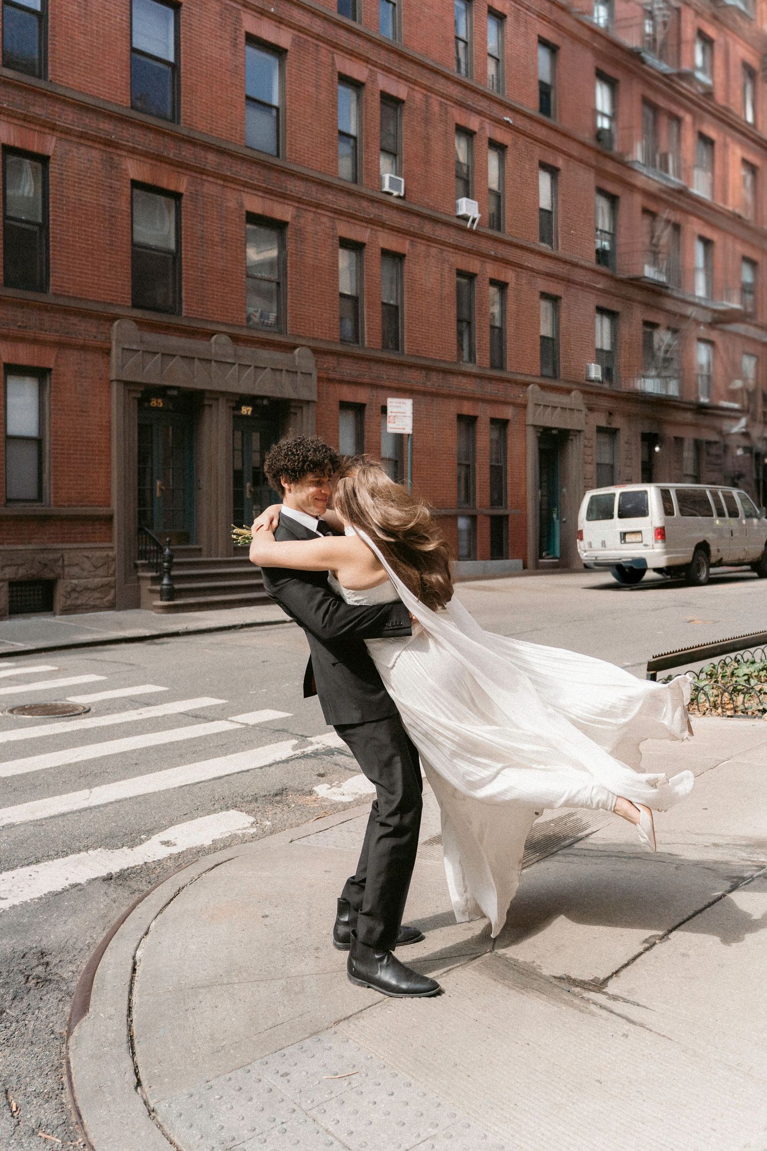 Artistic wedding dance sequence on city street with red brick buildings.