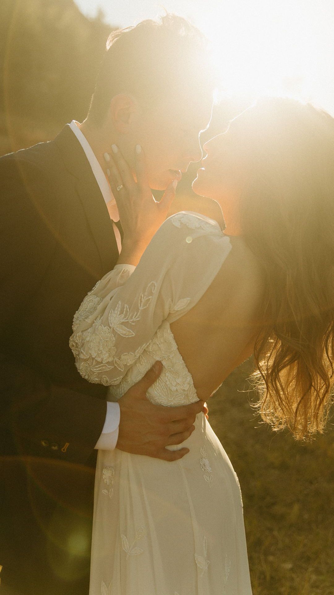 Romantic sunset portrait of newlyweds embracing in golden hour light.