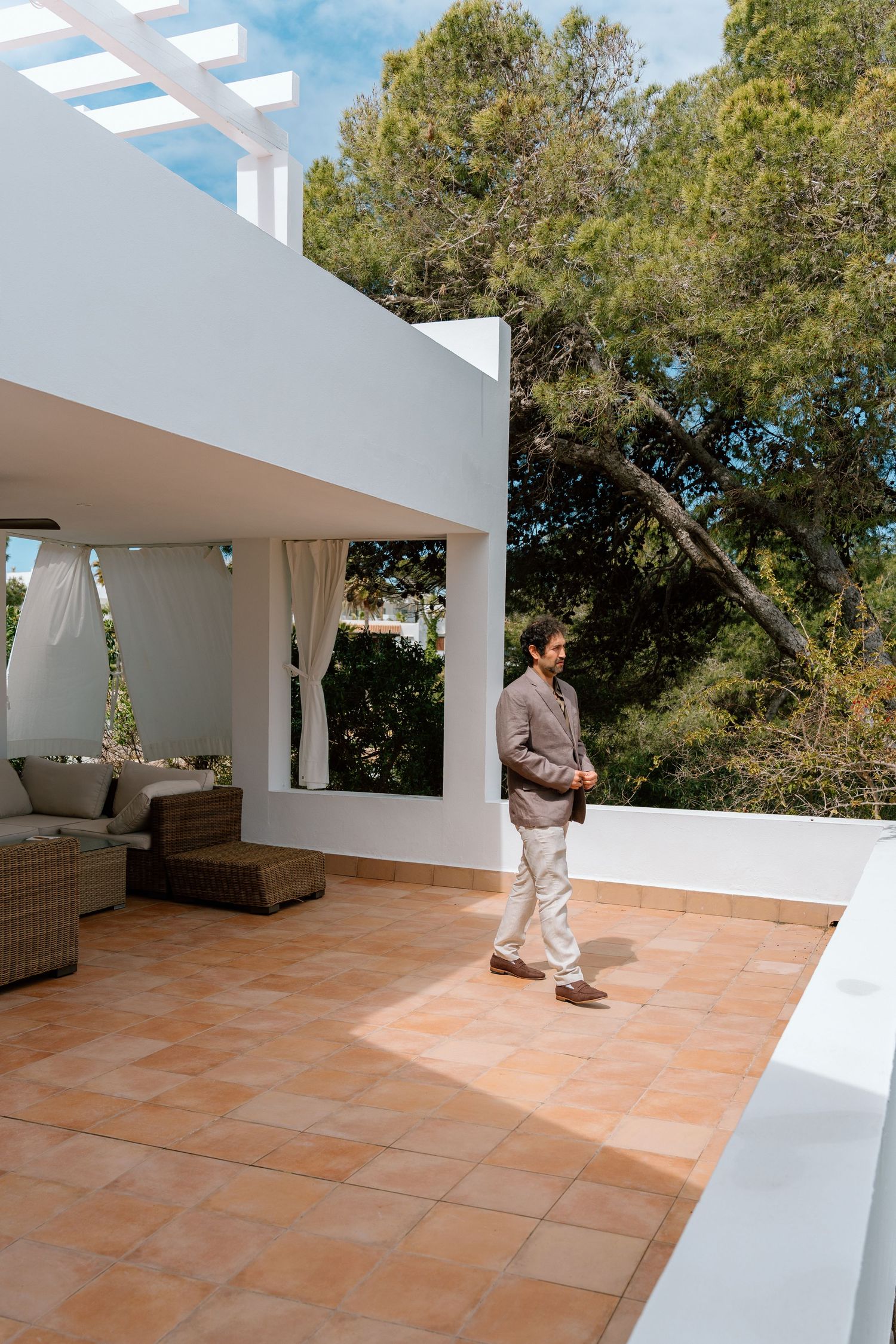 Modern terrace with terra cotta tiles and white walls overlooking nature.