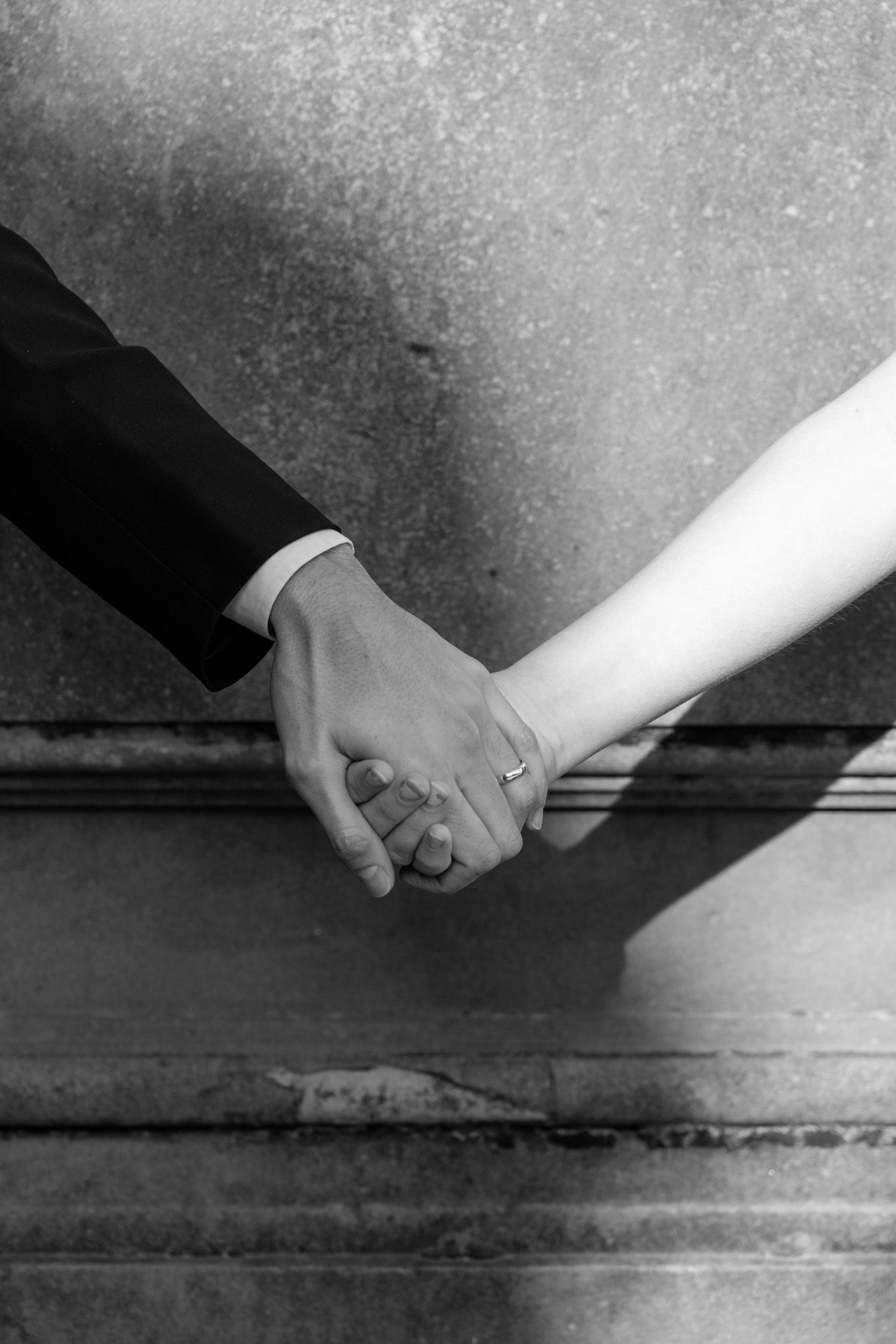 Close-up of hands reaching toward each other against textured background.