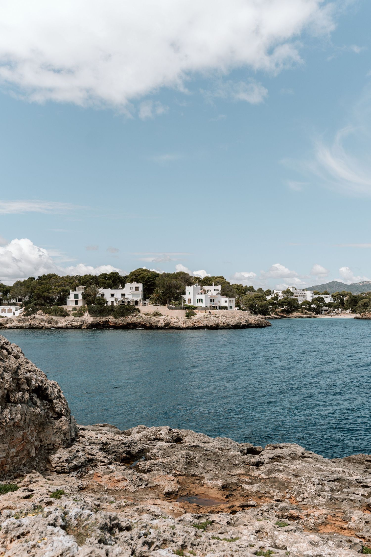 Scenic coastal view of white Mediterranean villas nestled along rocky shoreline with blue waters.