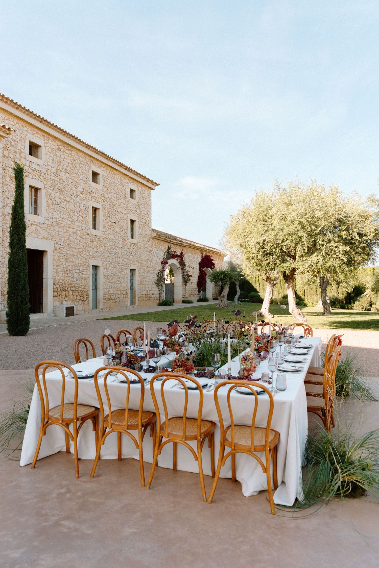 Outdoor wedding reception setup with wooden chairs and white tablecloths at a Mediterranean villa.