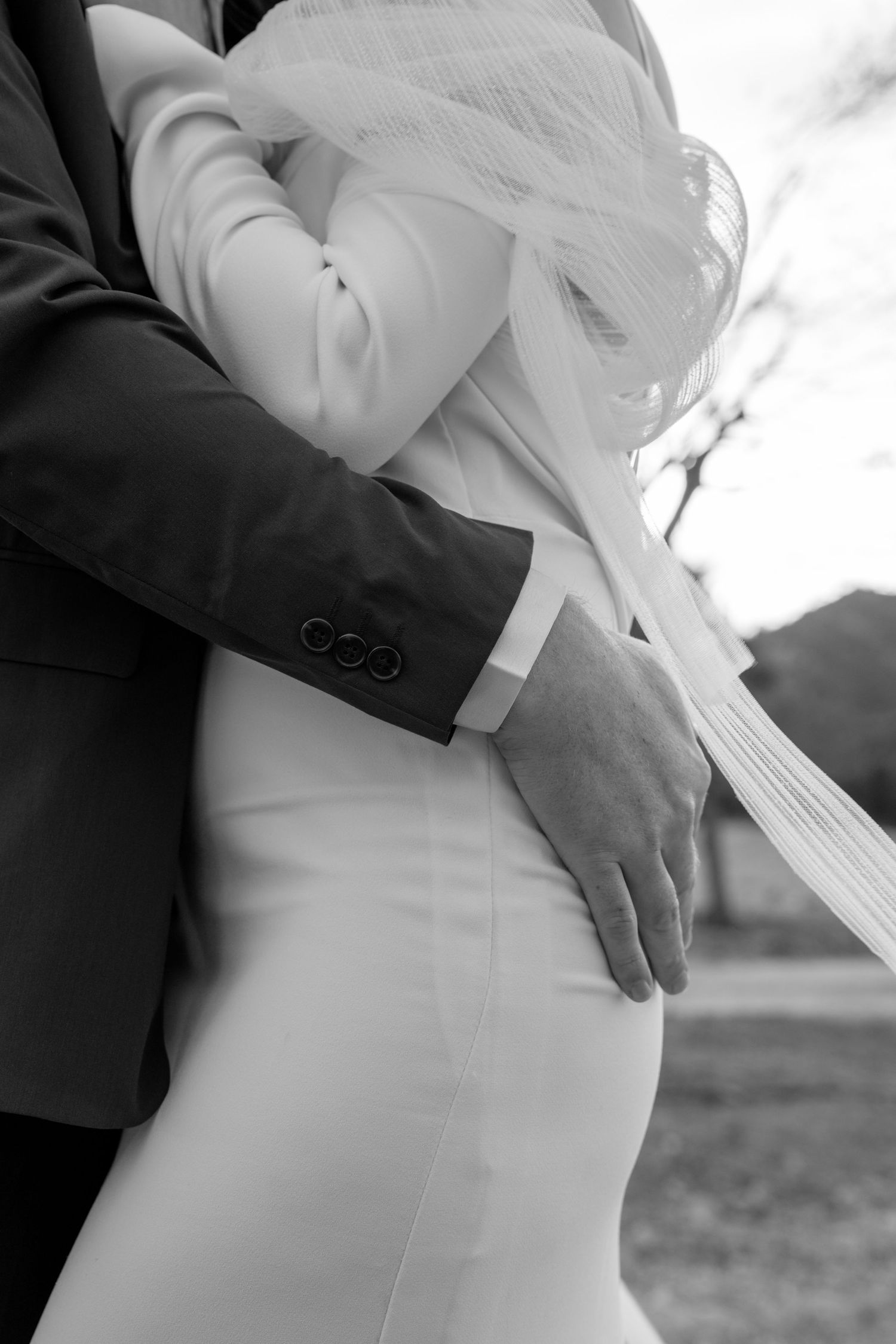 Close-up details of a white wedding dress silhouette against dark fabric.
