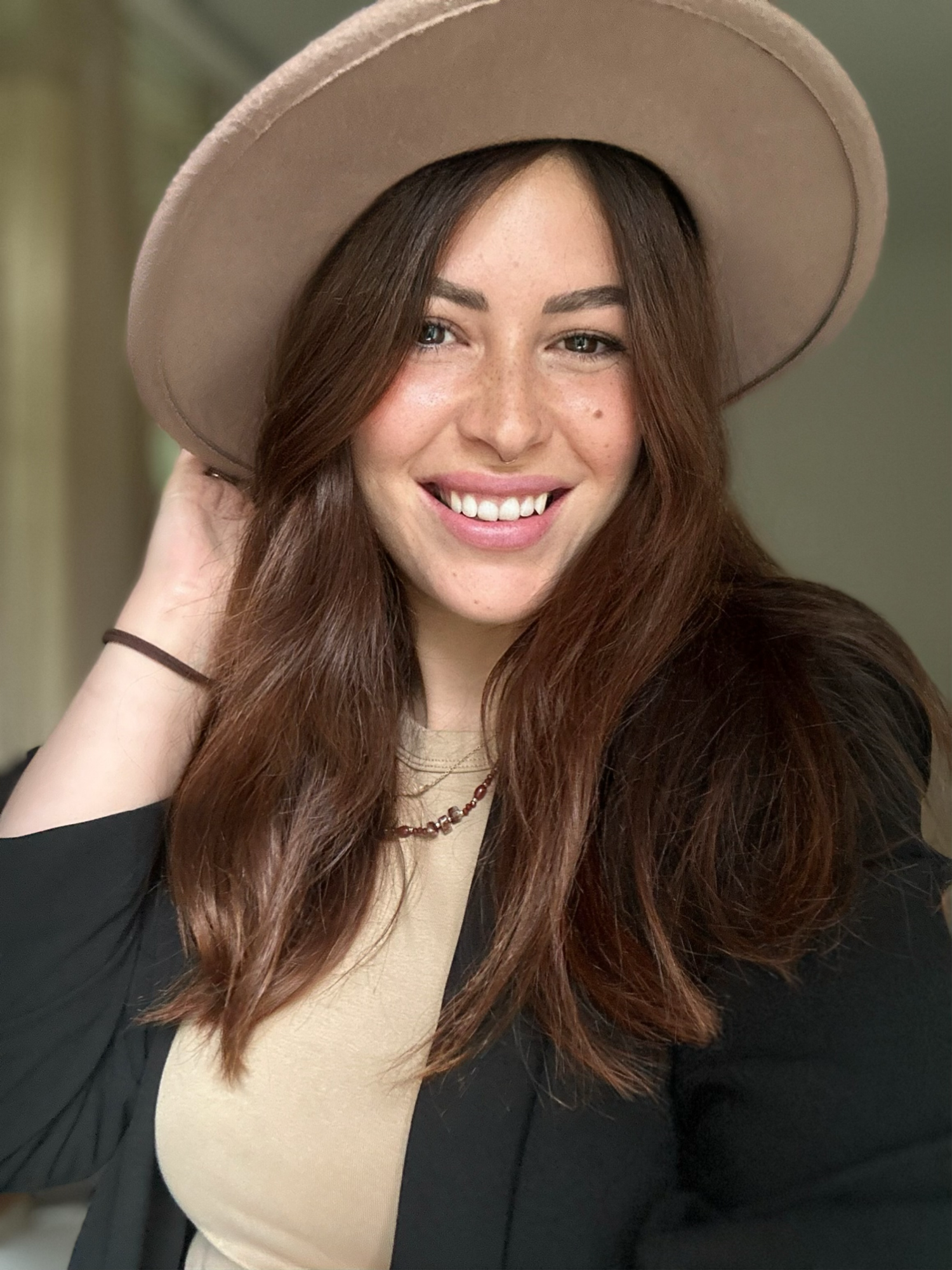 A series of portraits showing someone in a beige hat and black blazer with a bright smile.