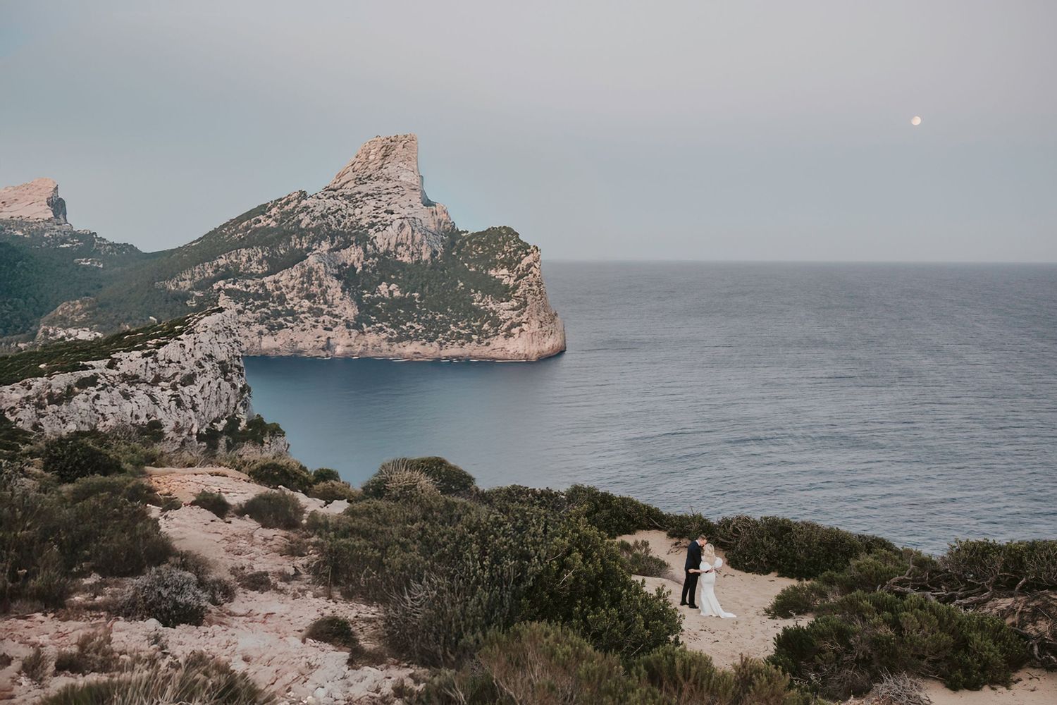 Scenic coastal landscape with dramatic cliffs and Mediterranean waters at sunset.