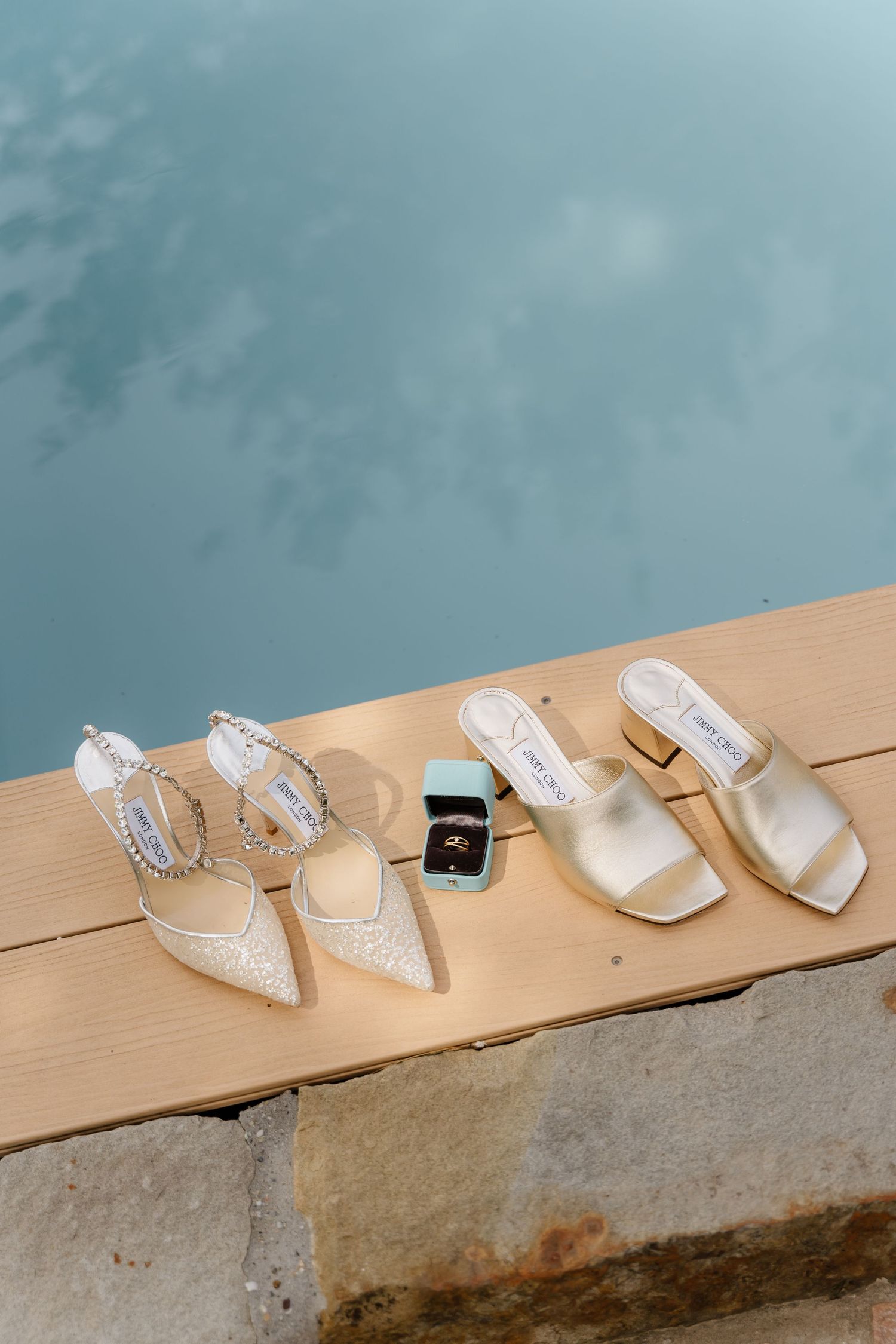 Wedding accessories including jewelry, shoes, and rings arranged on a wooden surface.