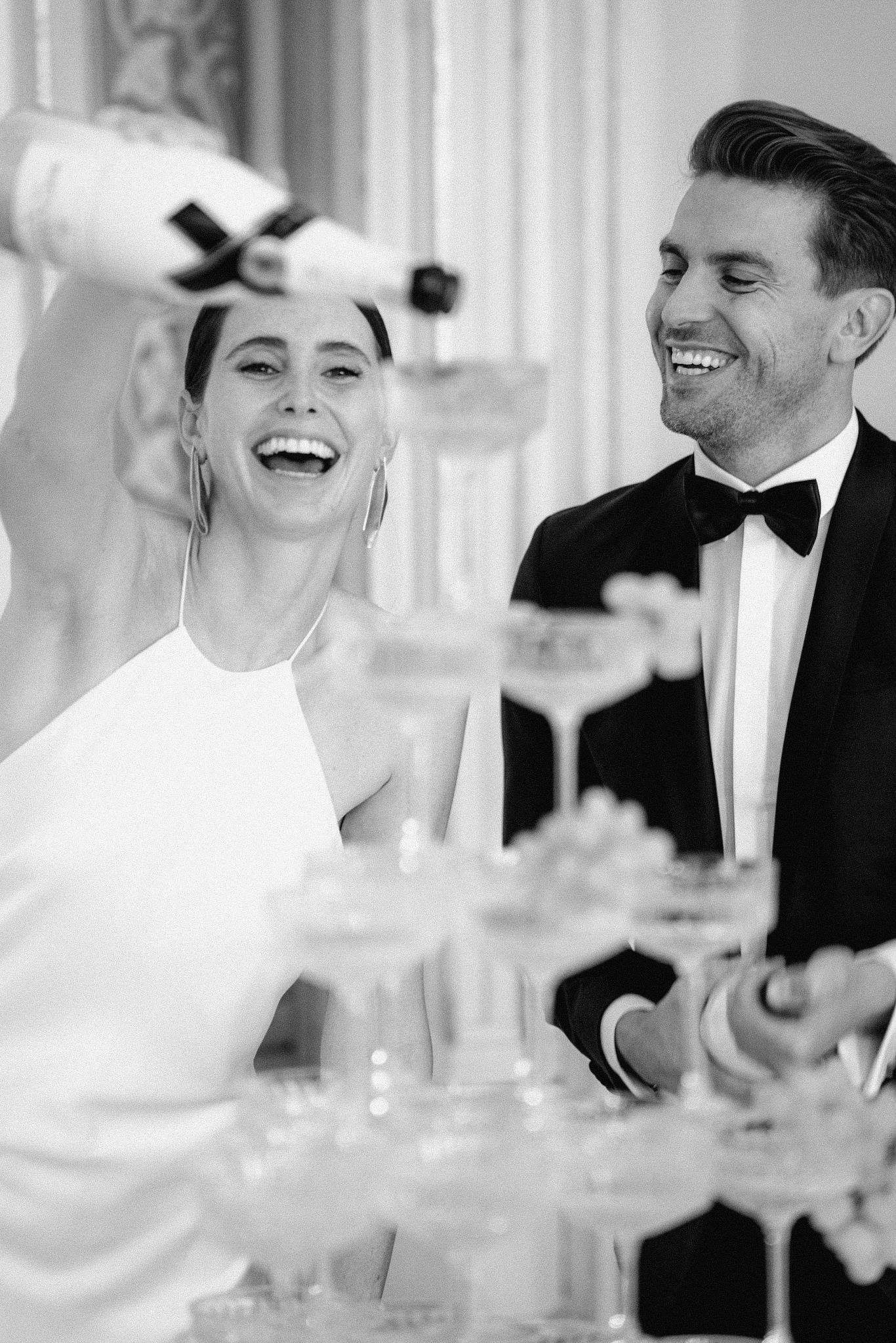 Black and white candid reception photo showing joyful laughter at formal event.