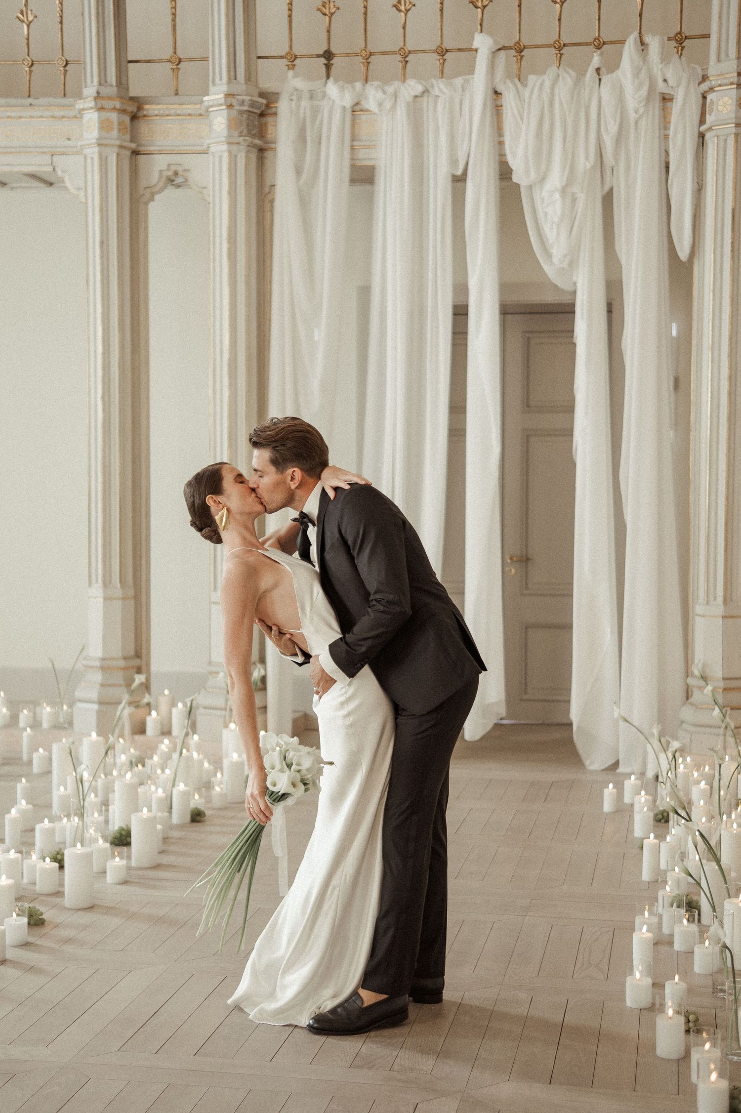 Elegant wedding photos in ornate white pillar hallway with candles.