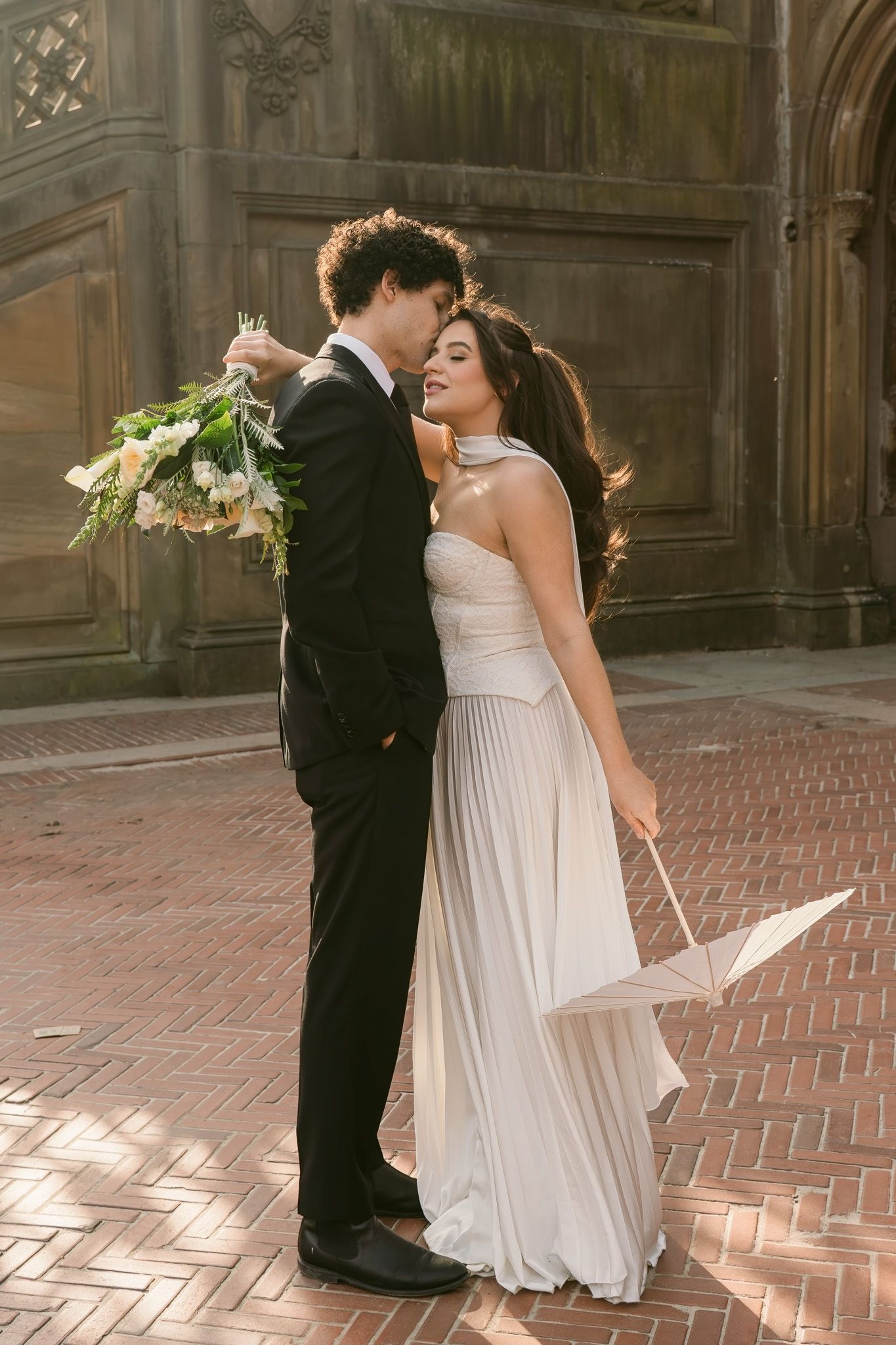 A couple in wedding attire shares an intimate dance moment on a historic brick terrace.
