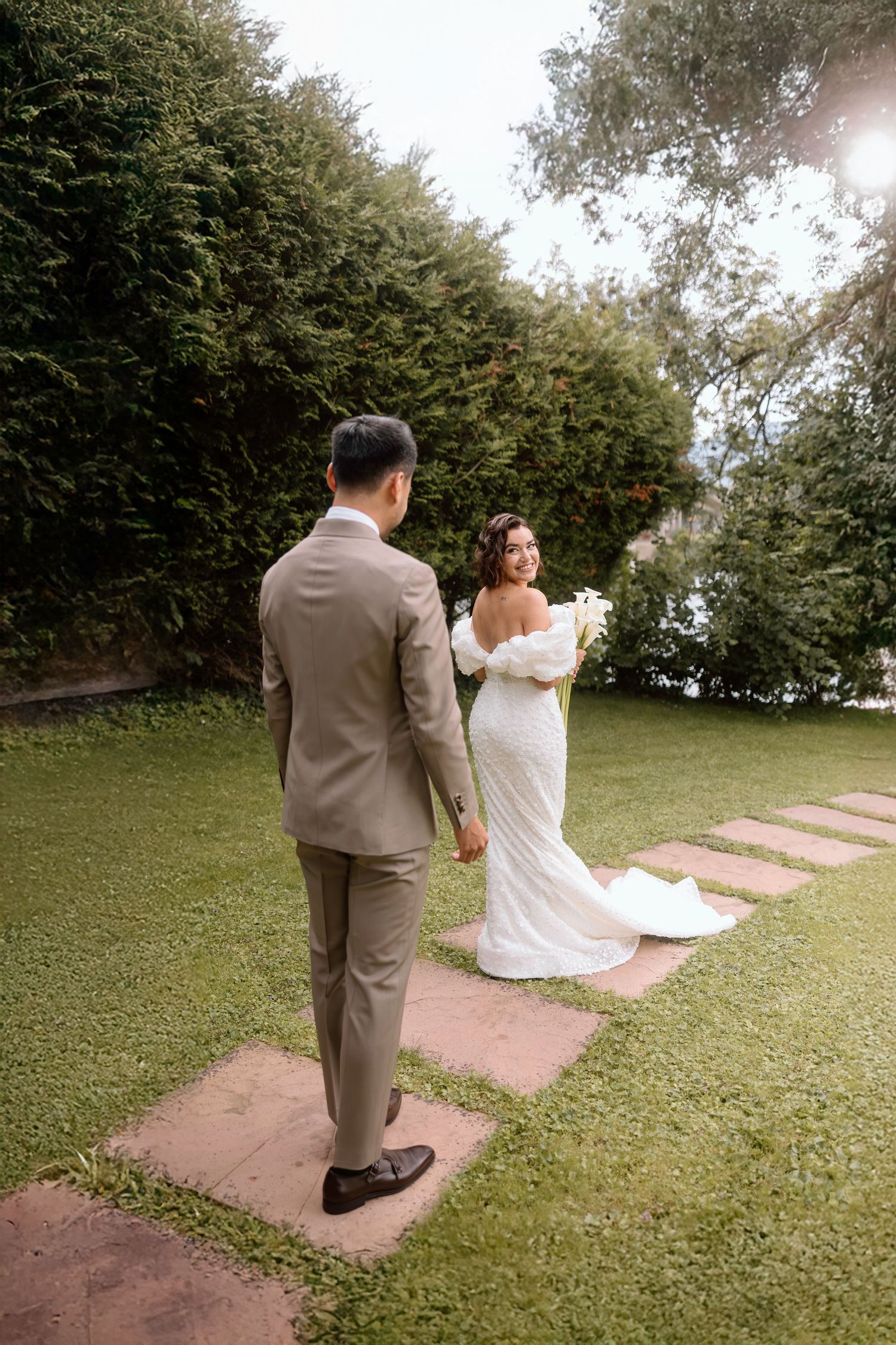 Couple walking along stone path surrounded by lush green landscaping.