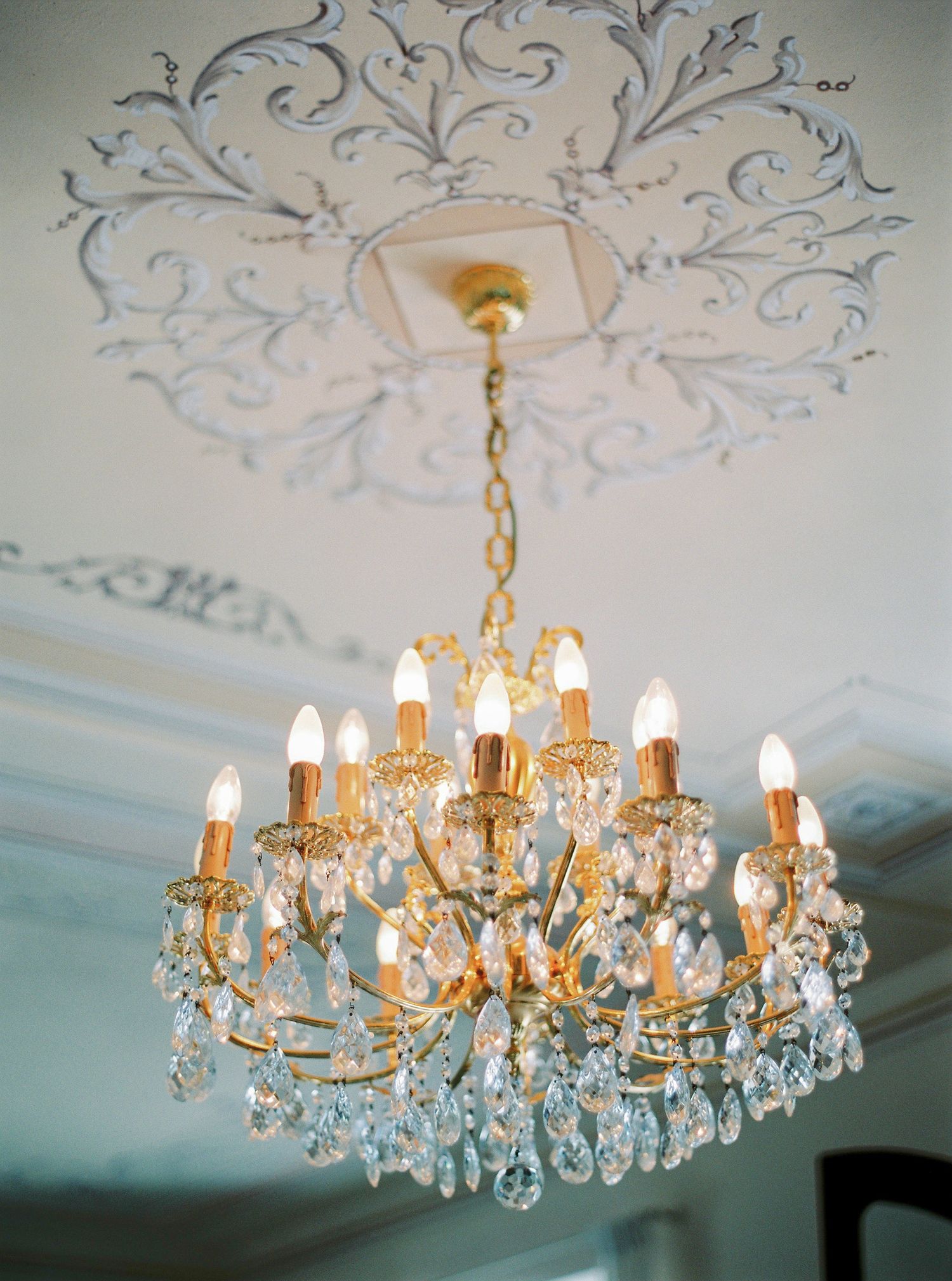 An ornate crystal chandelier with intricate ceiling details in a formal setting.