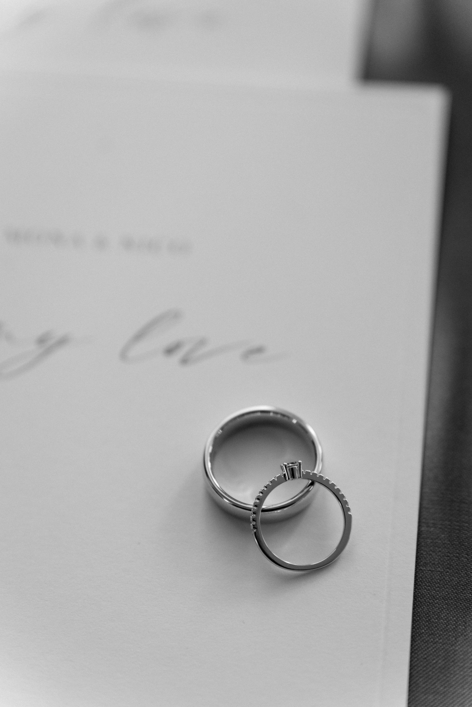 Wedding rings photographed on white paper with elegant calligraphy.