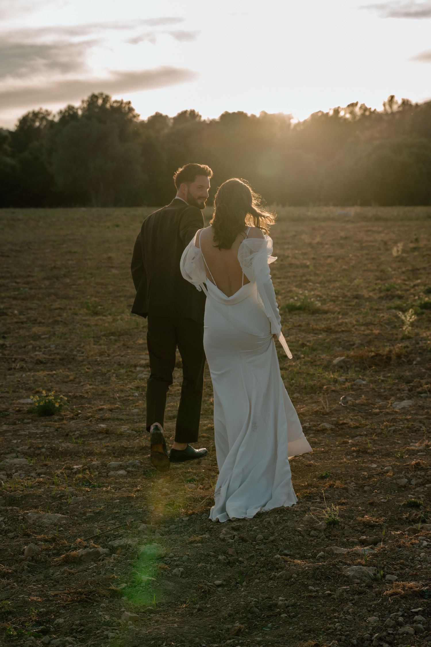 Sunset wedding photoshoot in a rustic field with dramatic backlighting.