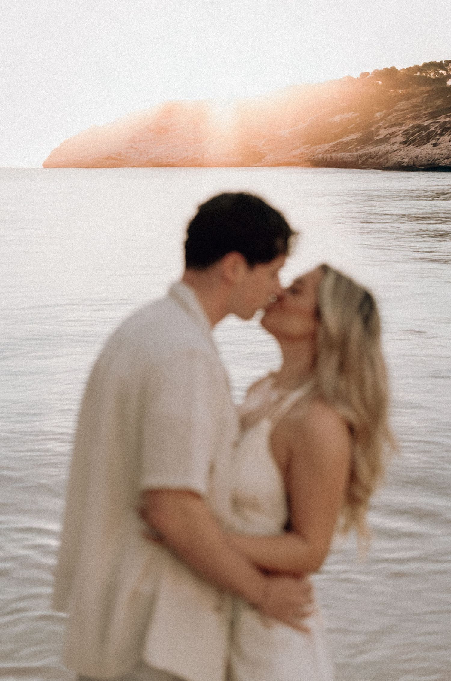 Romantic beach photoshoot at sunset with soft golden light and ocean backdrop.