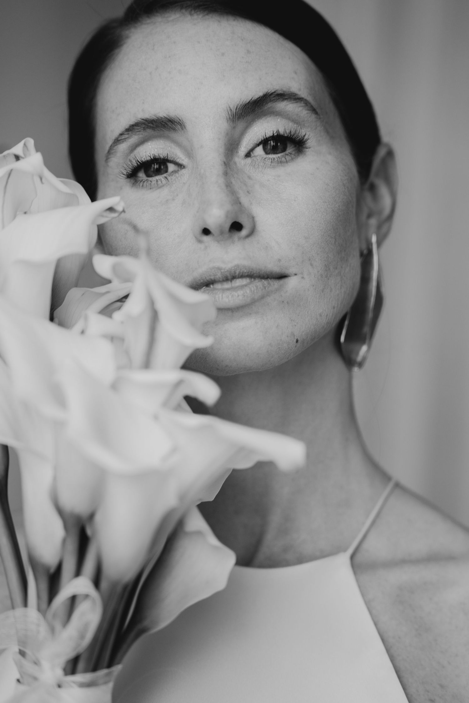 A black and white close-up portrait with elegant calla lily flowers creating an artistic composition.