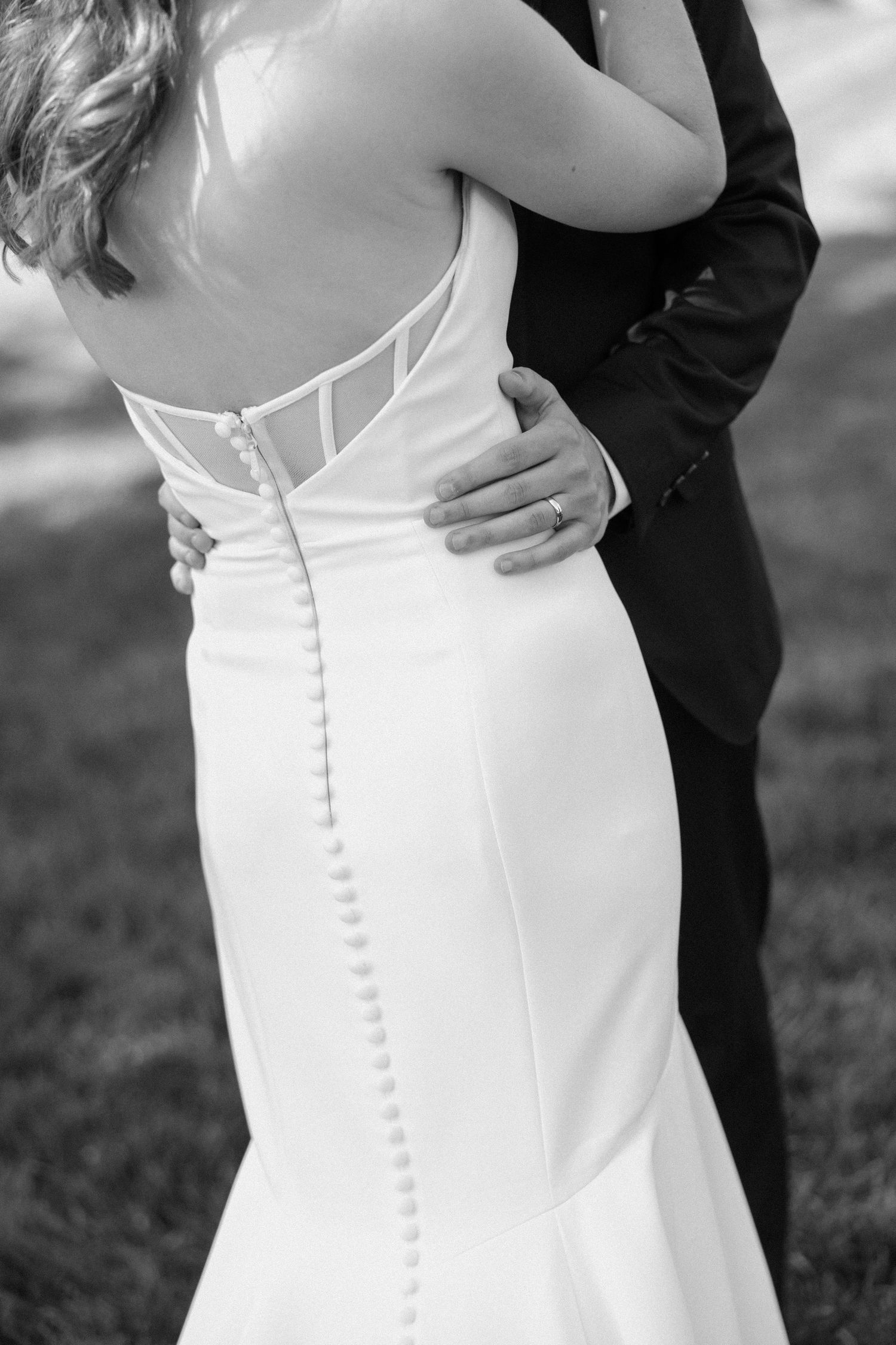 Close-up details of a white wedding dress with delicate button accents.