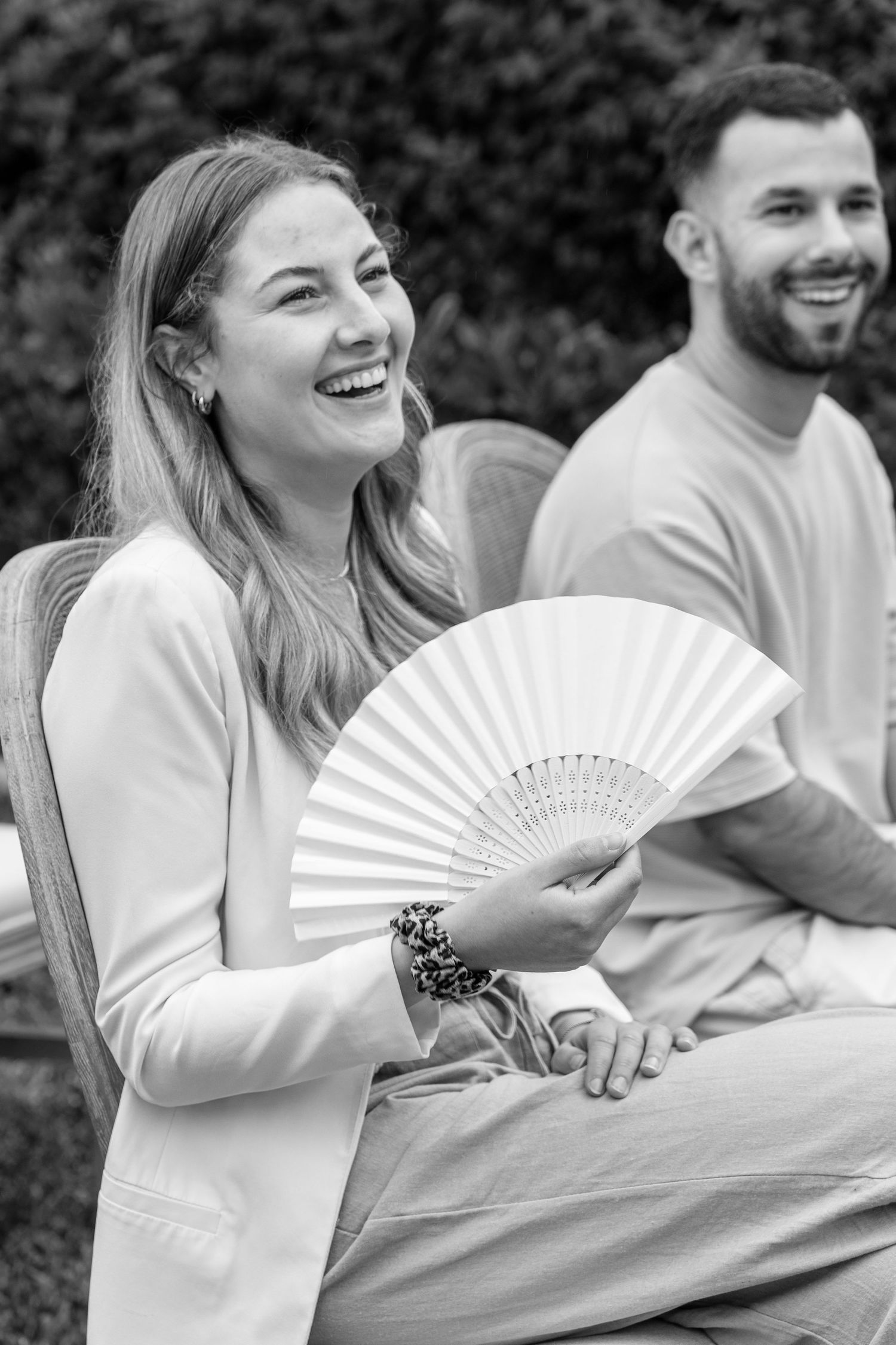 Wedding party guests in white attire sharing joyful moments with decorative fans.