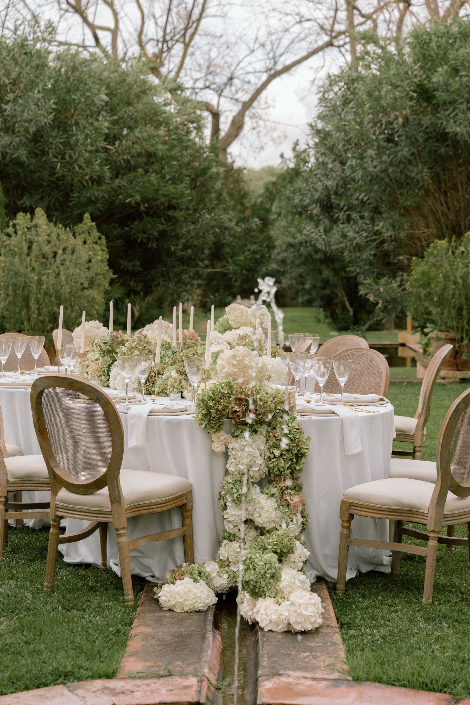 Elegant outdoor wedding reception setup with white tables and French country chairs.