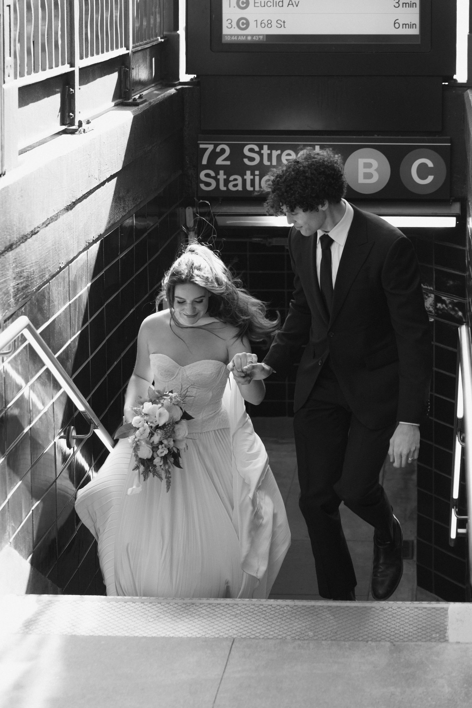 Wedding party descending subway station stairs in New York City.