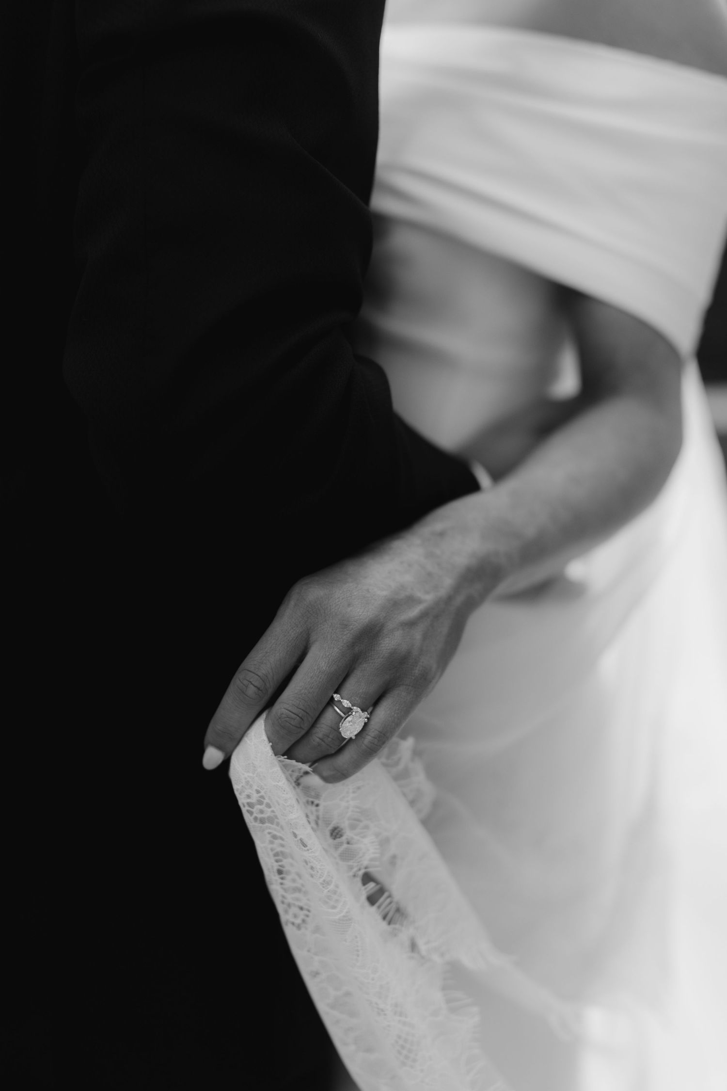 Close-up of delicate lace details and rings on white fabric.