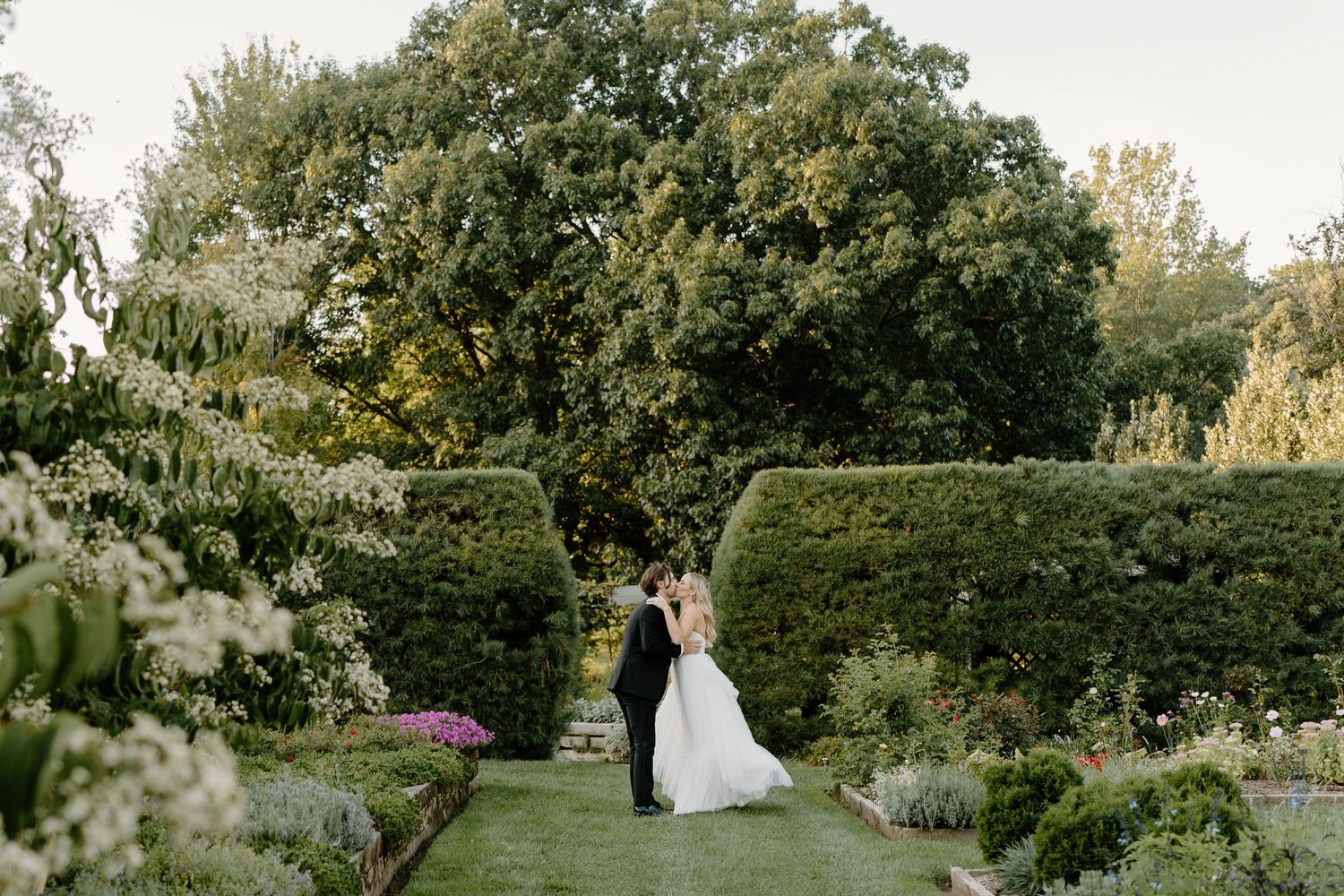 Wedding couple poses in a lush garden setting with beautiful greenery and natural lighting.
