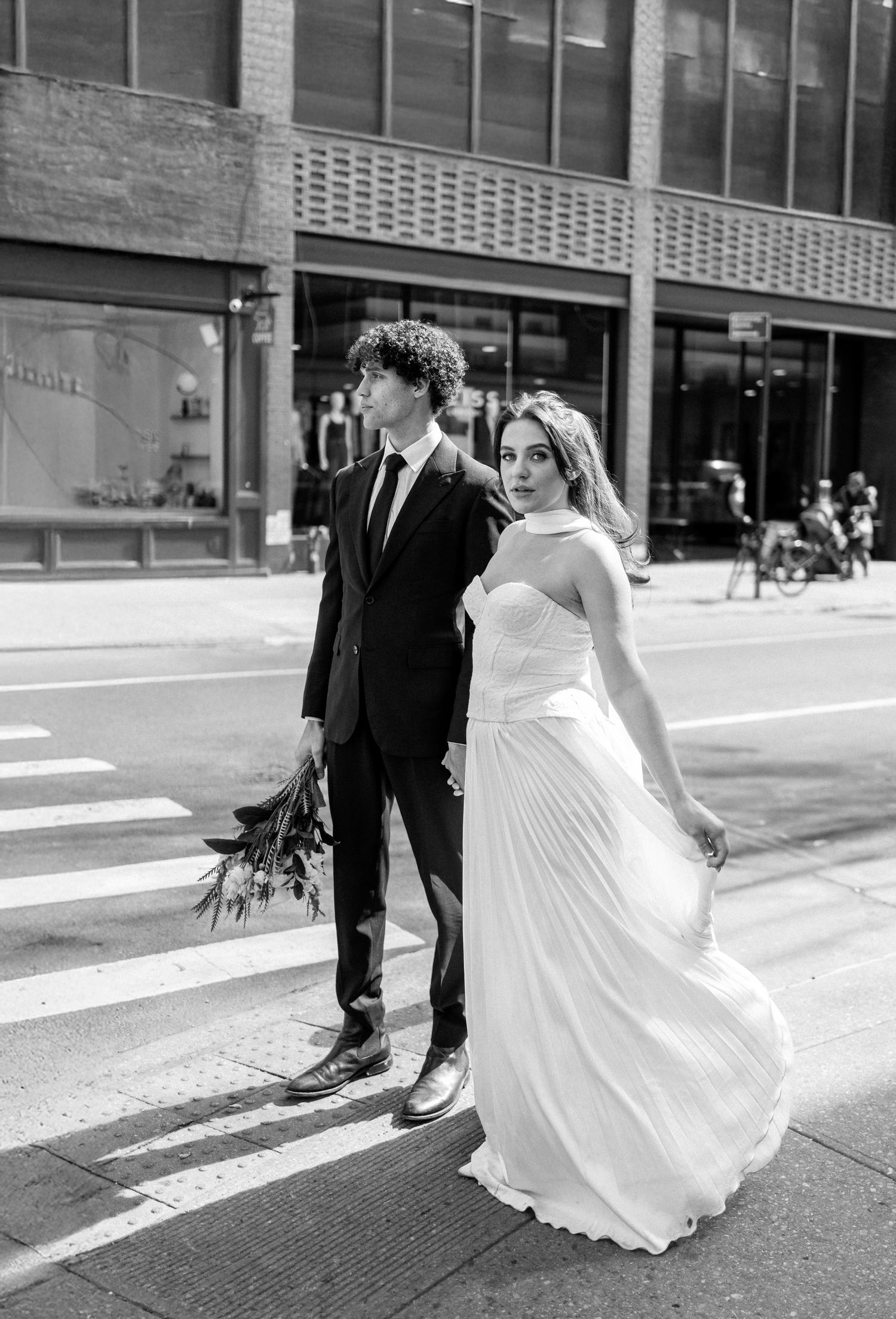 Wedding couple dancing in flowing white dress on urban crosswalk.
