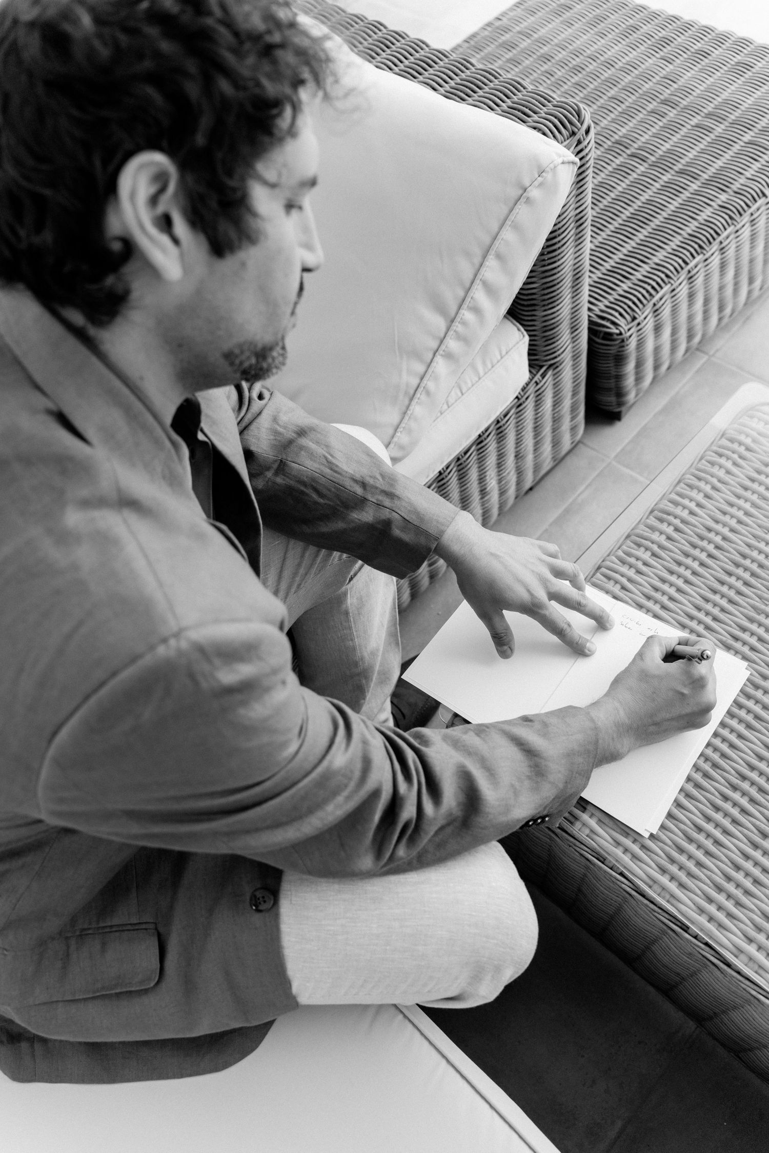 Person in formal attire writing in a notebook while seated.
