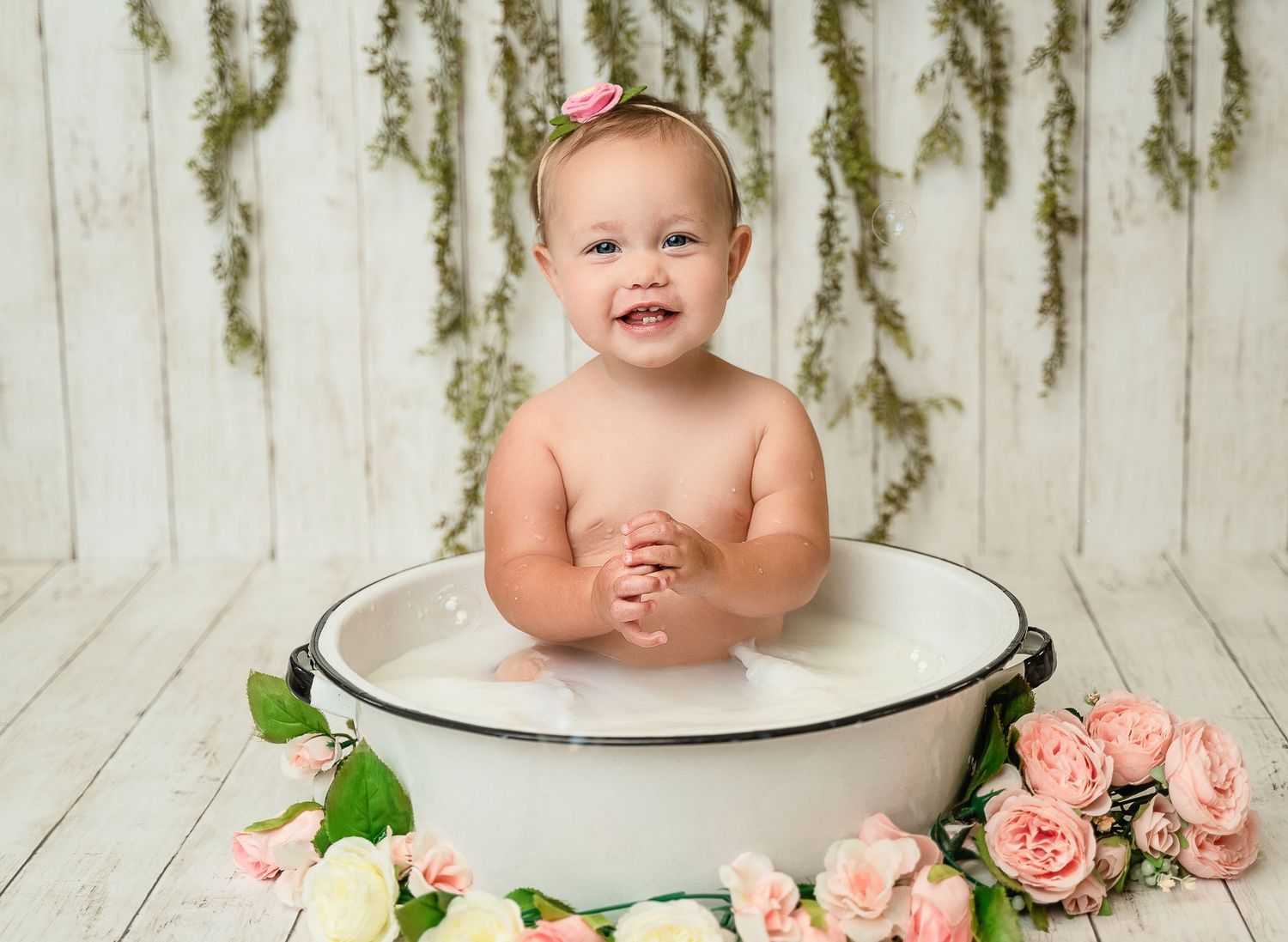 Vintage style portrait with enamel basin and pink roses against white wooden backdrop.