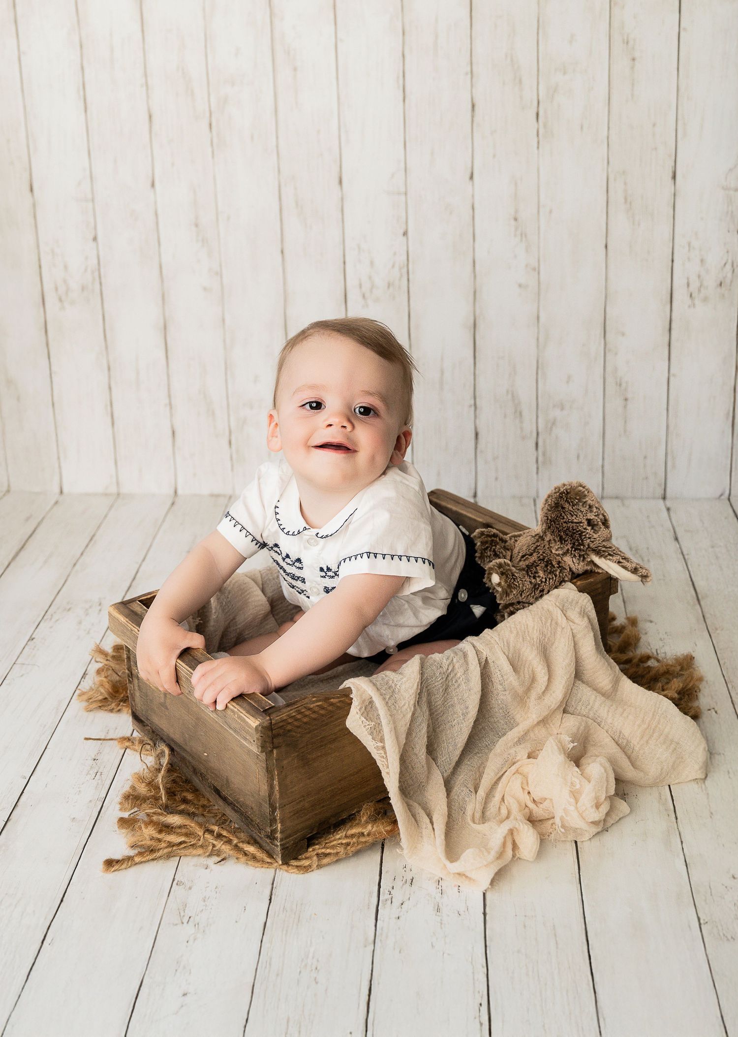 Studio photoshoot on wooden floor with rustic props and neutral tones.