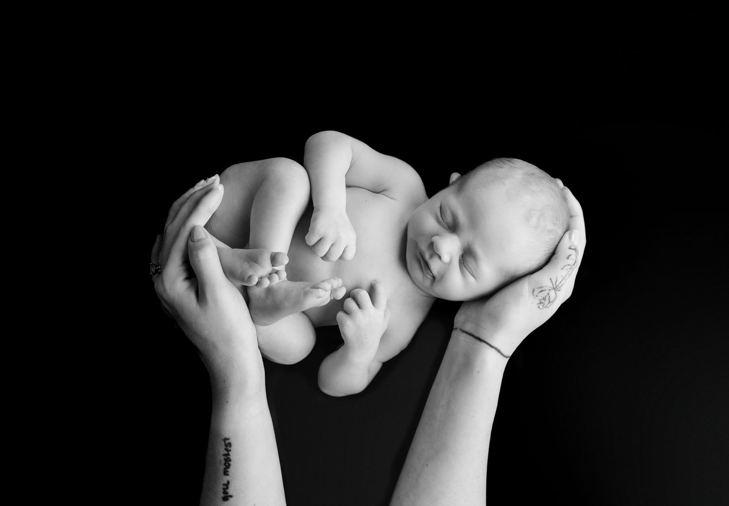 Black and white artistic photo series showing close-up details of tiny baby feet and hands against a dark background.