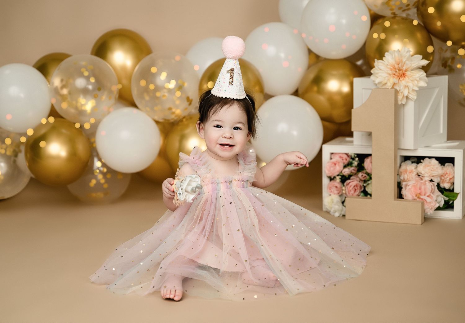 First birthday celebration with gold balloons, white cake, and pink accents.