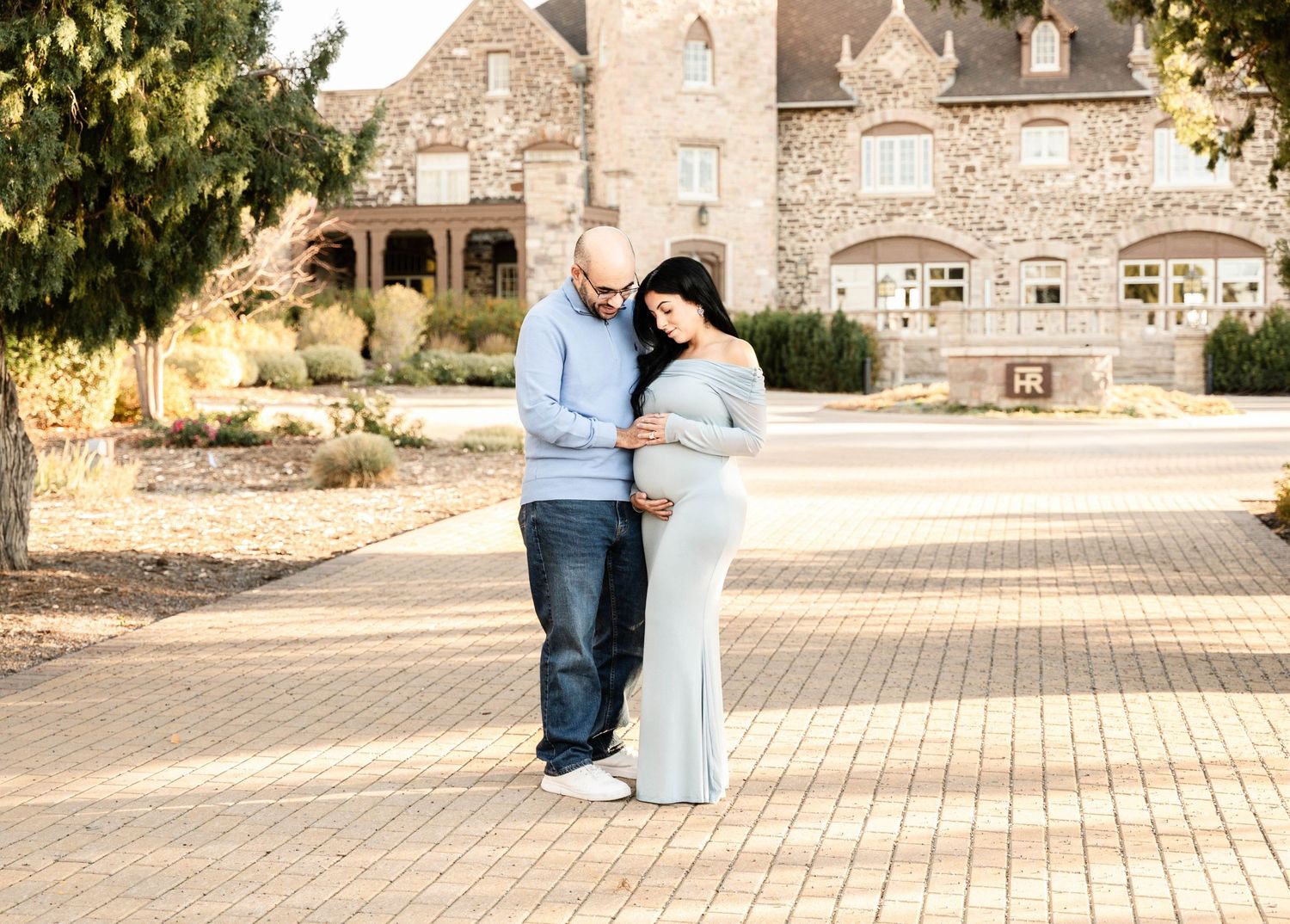 A couple shares a romantic moment together on a brick courtyard with a stone building in the background.