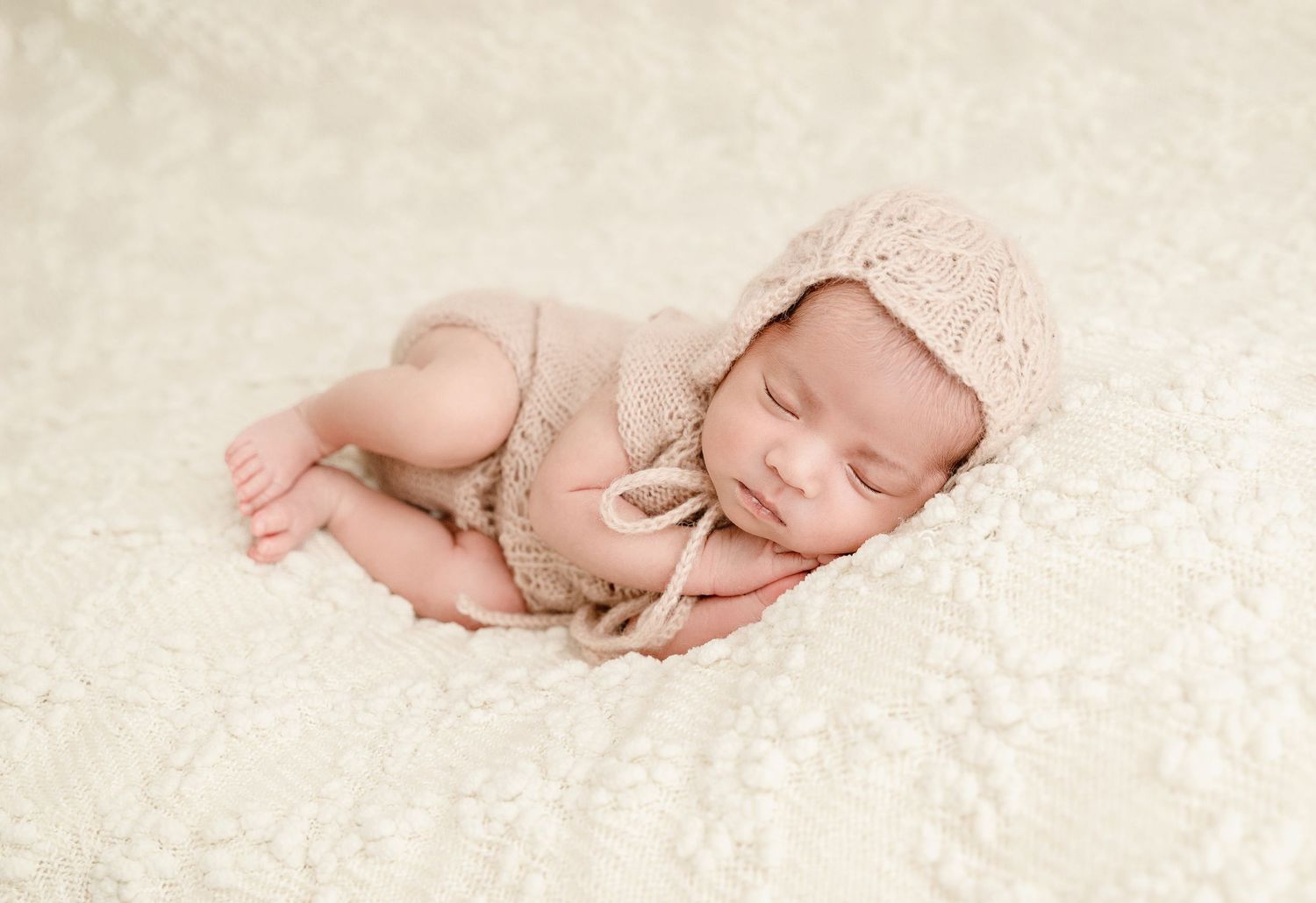 A series of peaceful sleeping newborn baby photos on soft cream colored blankets and textured backgrounds.