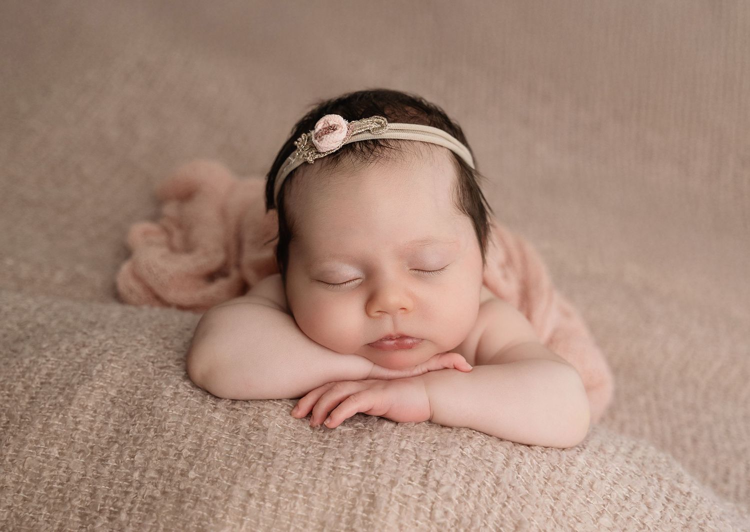 Artistic newborn portrait series on neutral textured backdrop.