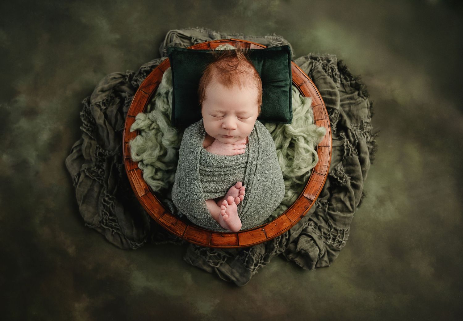 Four artistic newborn portrait shots with moody dark green backdrop and textured fabric swaddle wraps.