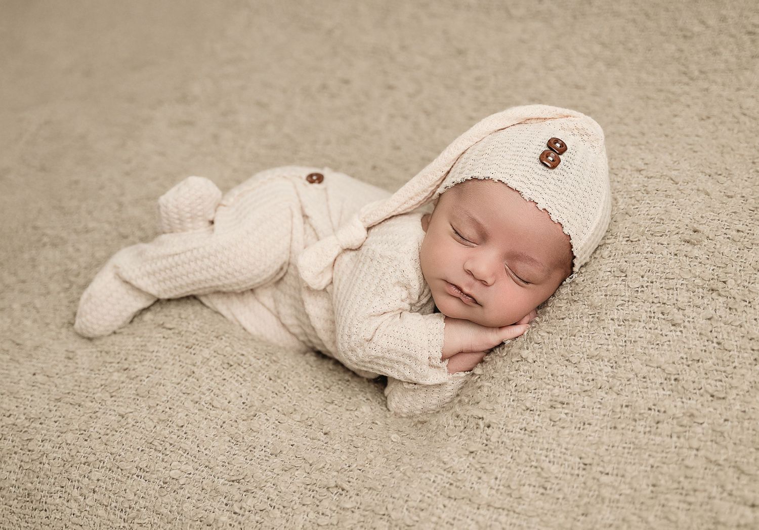 Peaceful sleeping baby wearing cozy white knit bunny outfit.