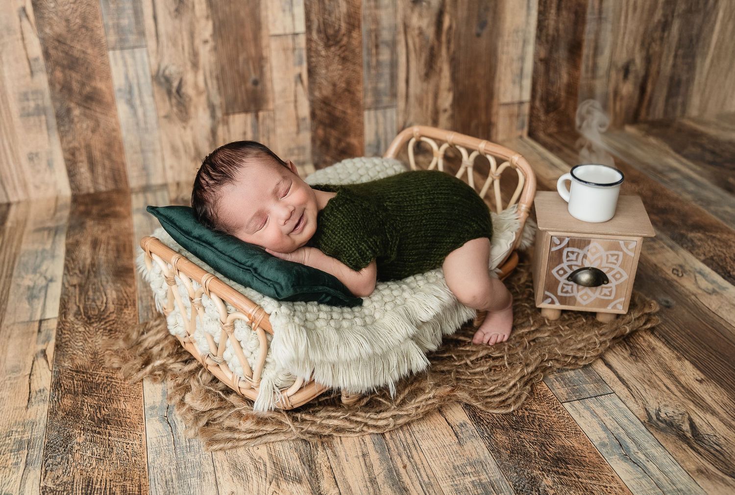 Professional newborn photographer arranges rustic wooden floral scene with vintage styling elements.