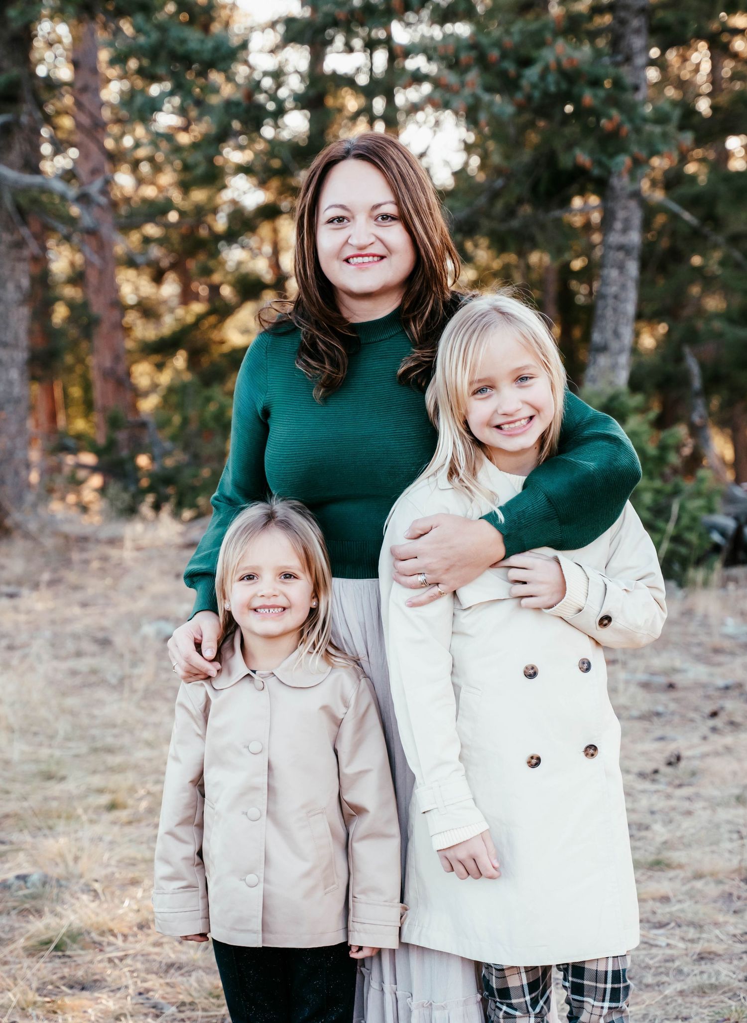 A candid outdoor family photoshoot in autumn featuring coordinated green and cream outfits against a natural backdrop.