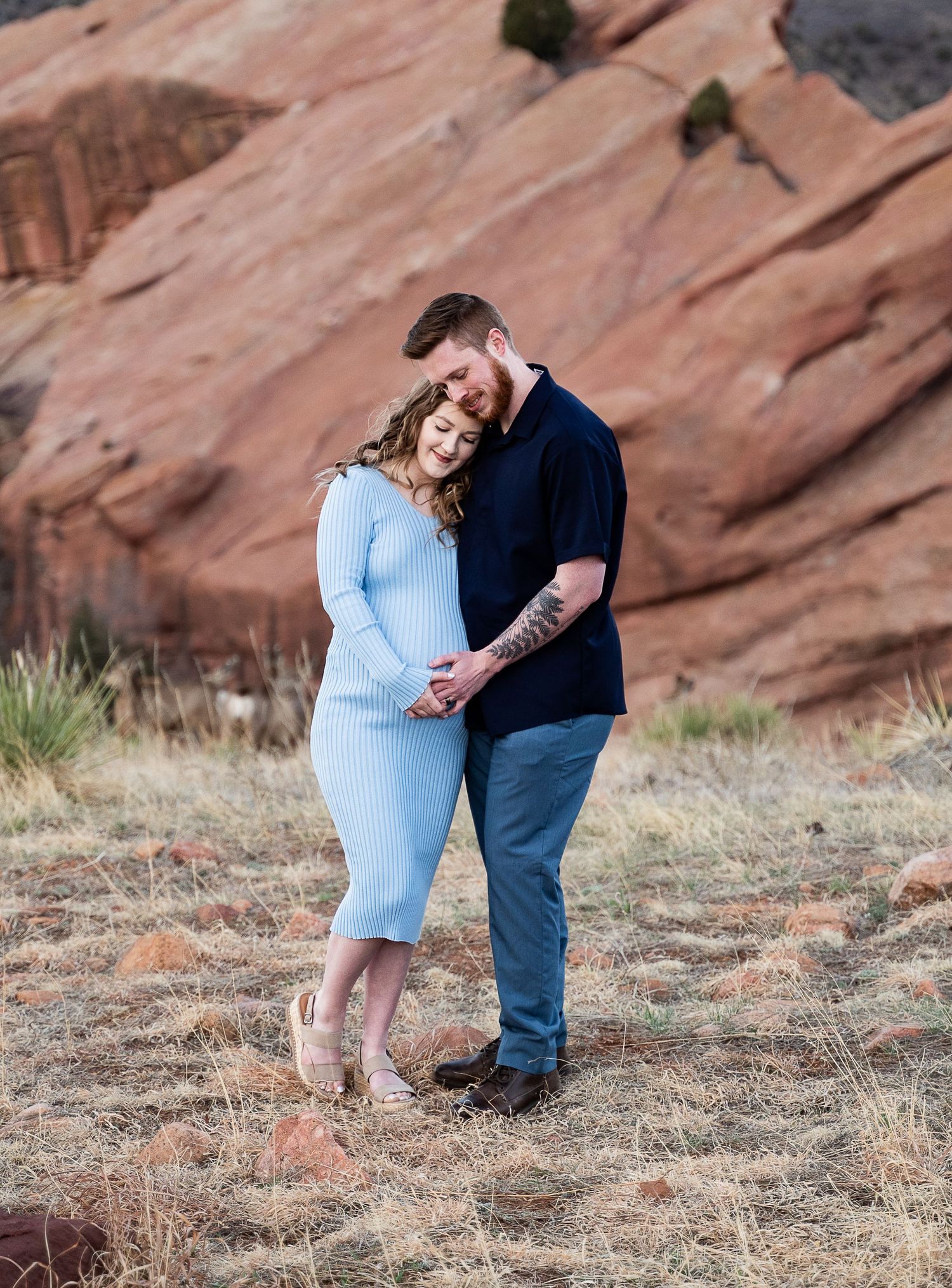 A loving couple poses together against red rock formations during their photoshoot.