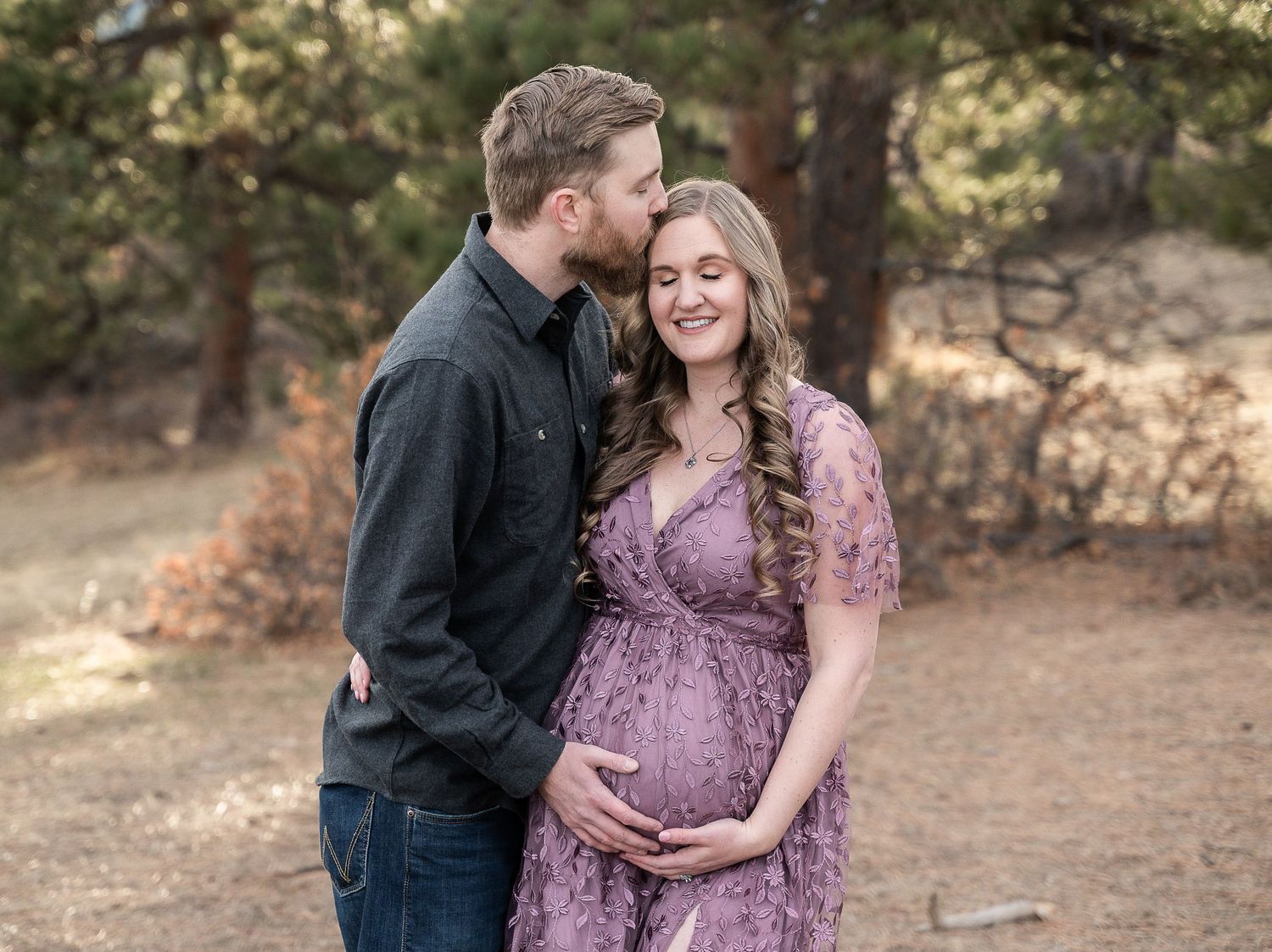 Romantic outdoor maternity photoshoot with couple among autumn trees at sunset.