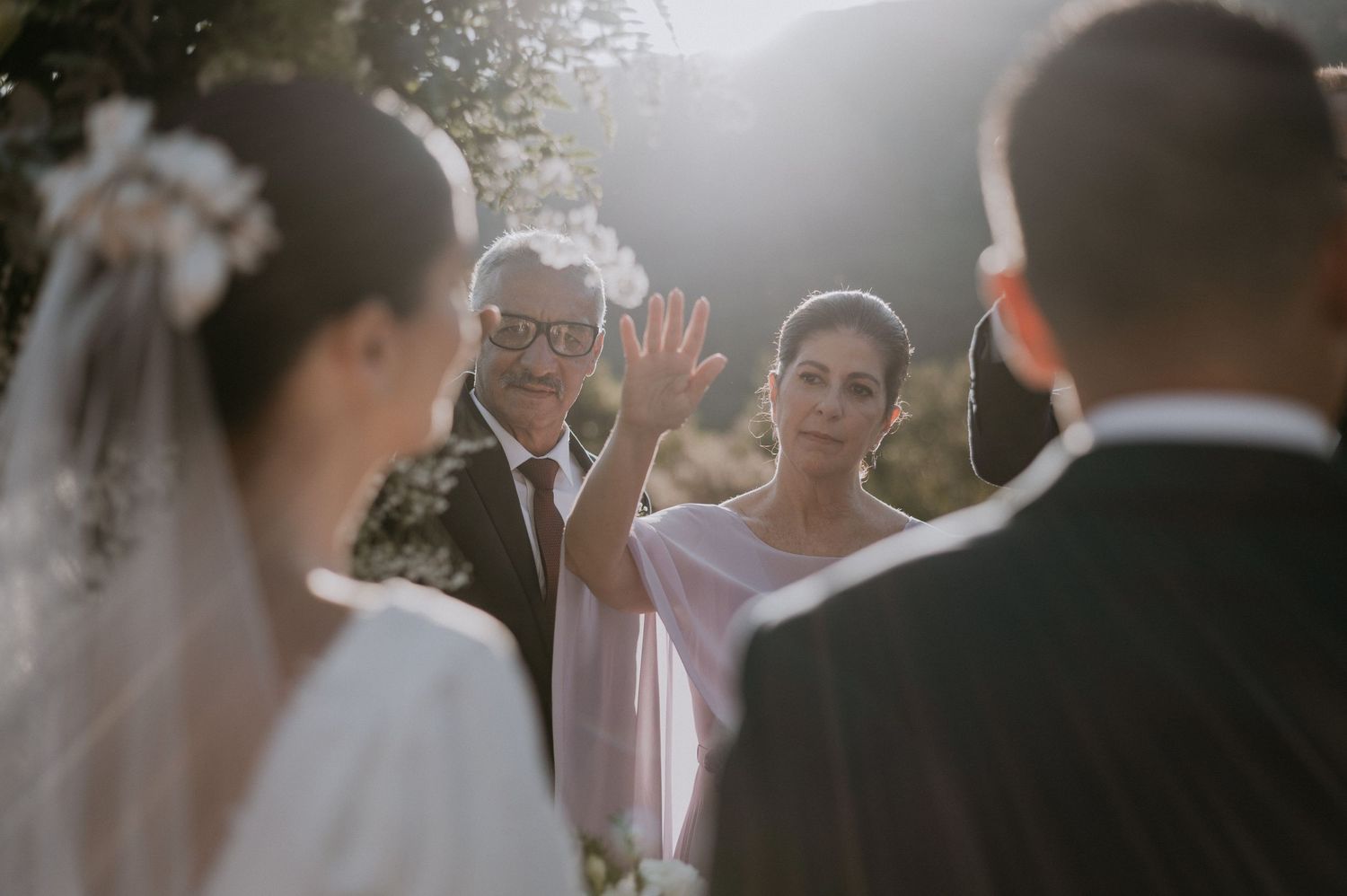 Outdoor wedding ceremony with guests and officiant in golden afternoon light.