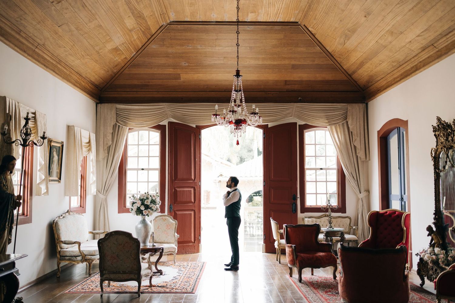 Elegant room with wooden ceiling, antique furniture and large windows casting natural light into an airy interior.