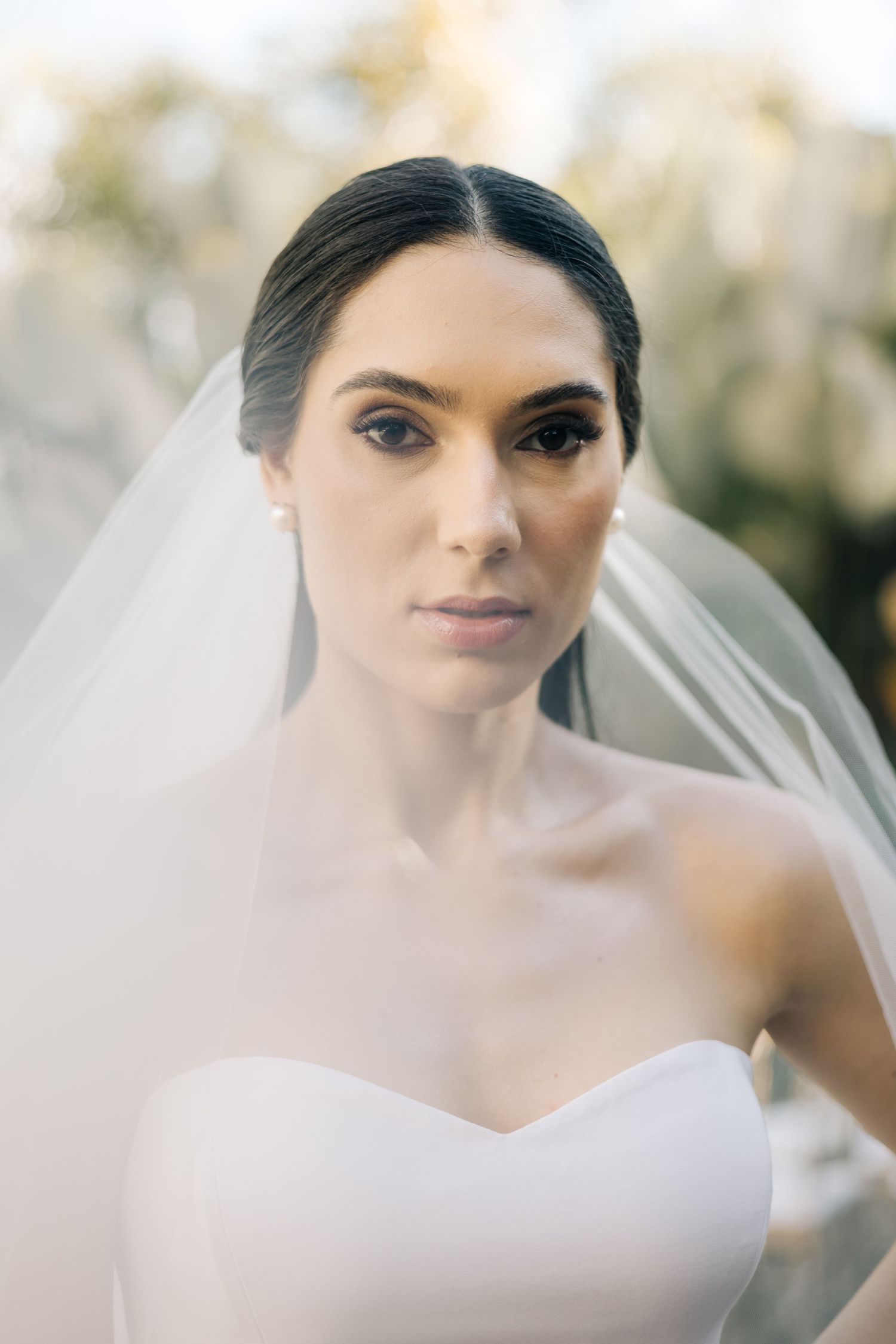 A stunning black and white portrait series of a bride wearing an ethereal veil in natural lighting.