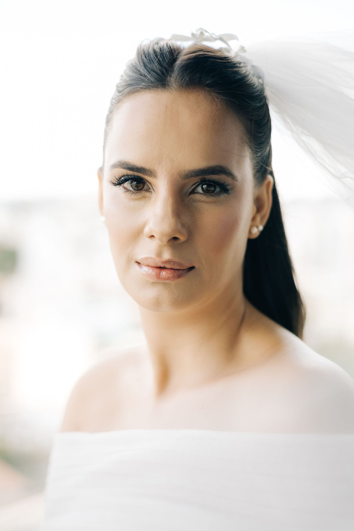 Close-up bridal portrait with delicate veil and off-shoulder dress.