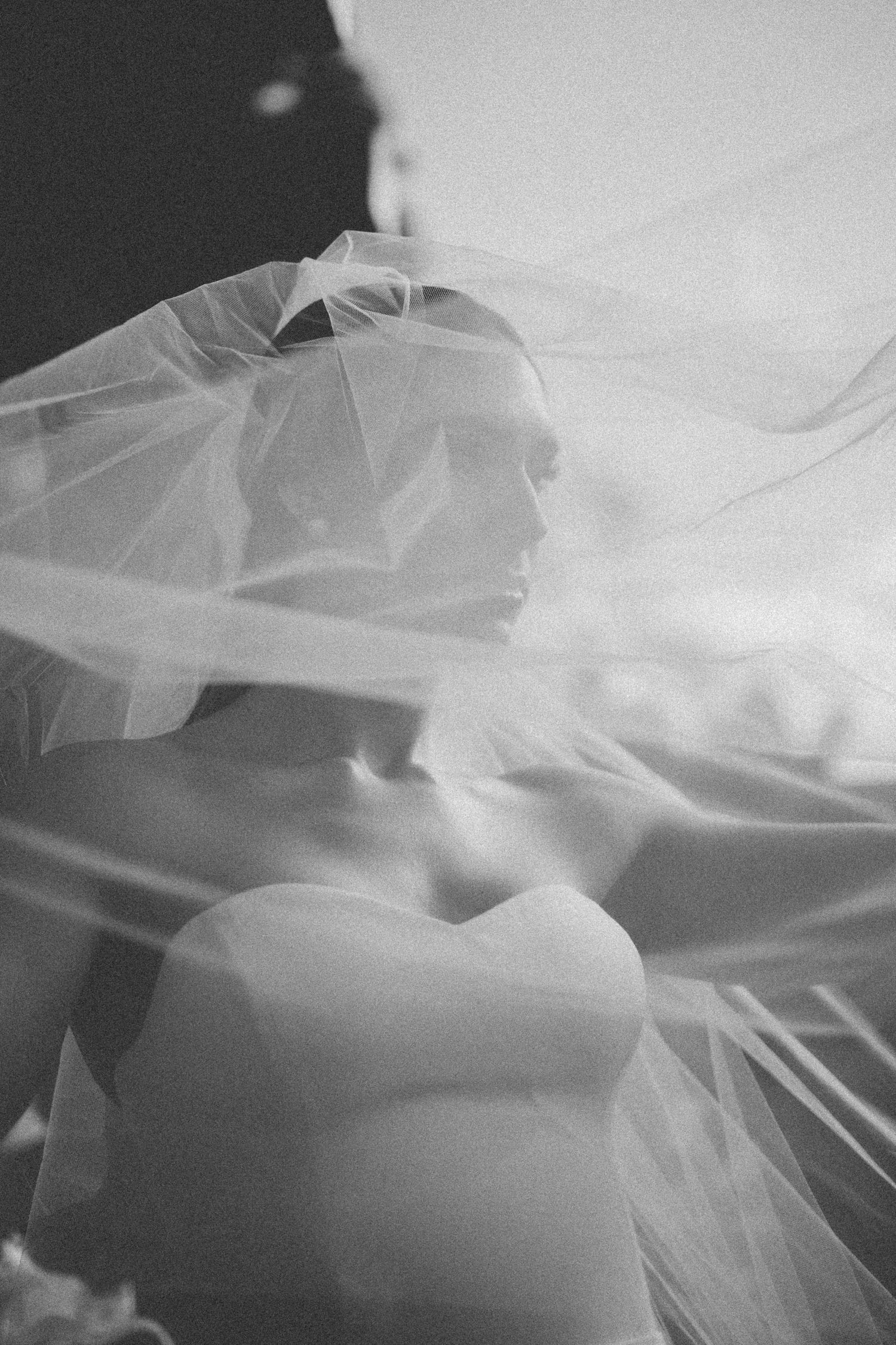 An artistic black and white bridal portrait with ethereal veil wrapped softly around the silhouette.